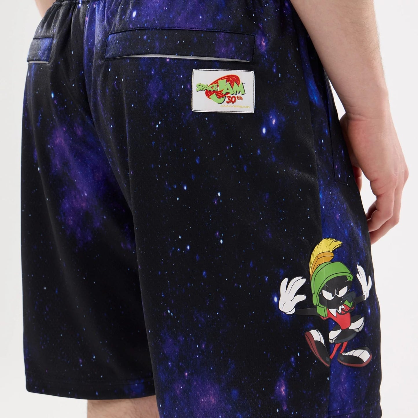 New Era Space Jam Warner Brothers Space Jam White Oversized Shorts, back view showing a dark space pattern with Marvin the Martian graphic on the side and an embroidered Space Jam 30th Anniversary patch above the pocket.