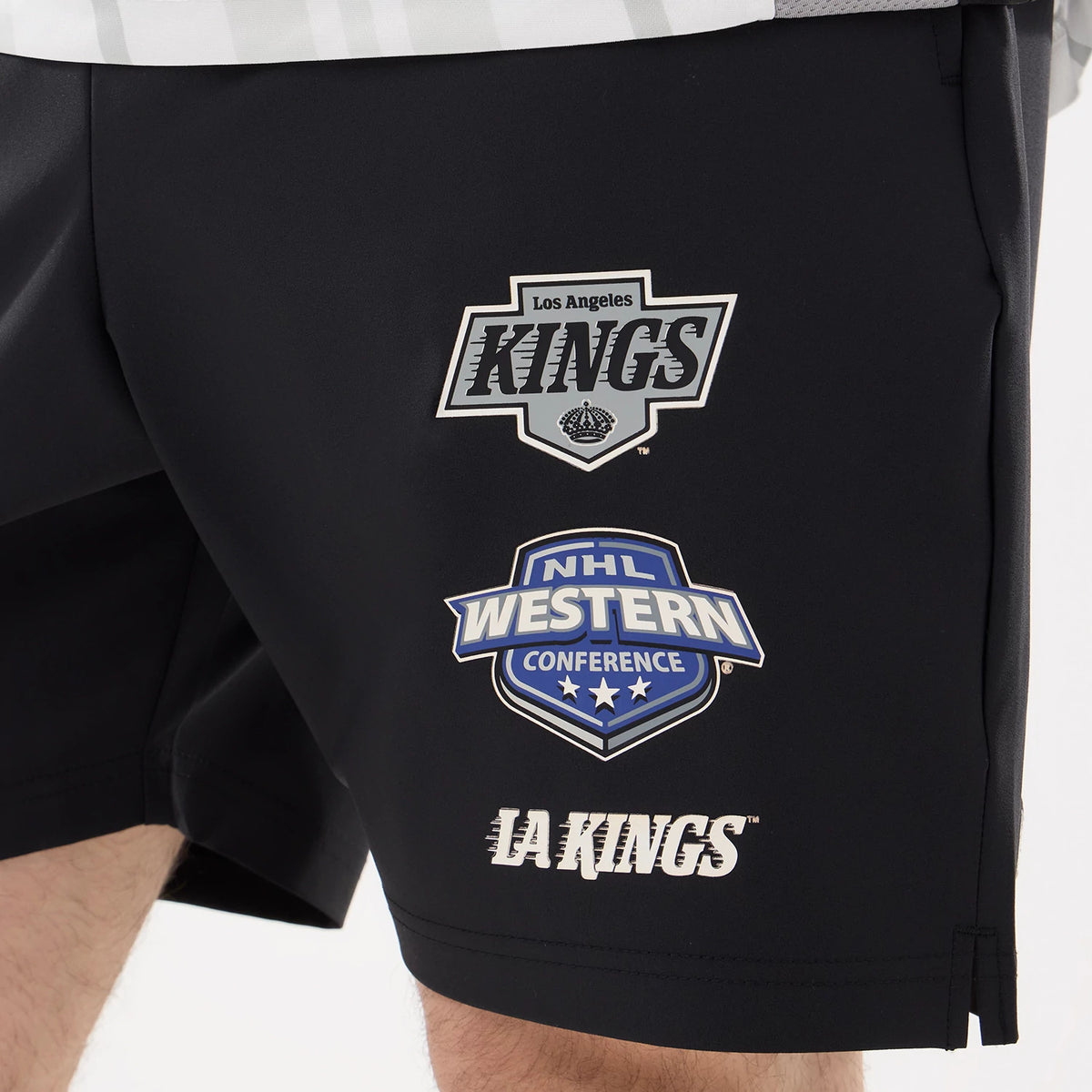 New Era LA Kings NHL Match Black Oversized Shorts, front view showing printed logos including Los Angeles Kings shield on the upper right leg and NHL Western Conference below, with LA Kings lettering near the hem.