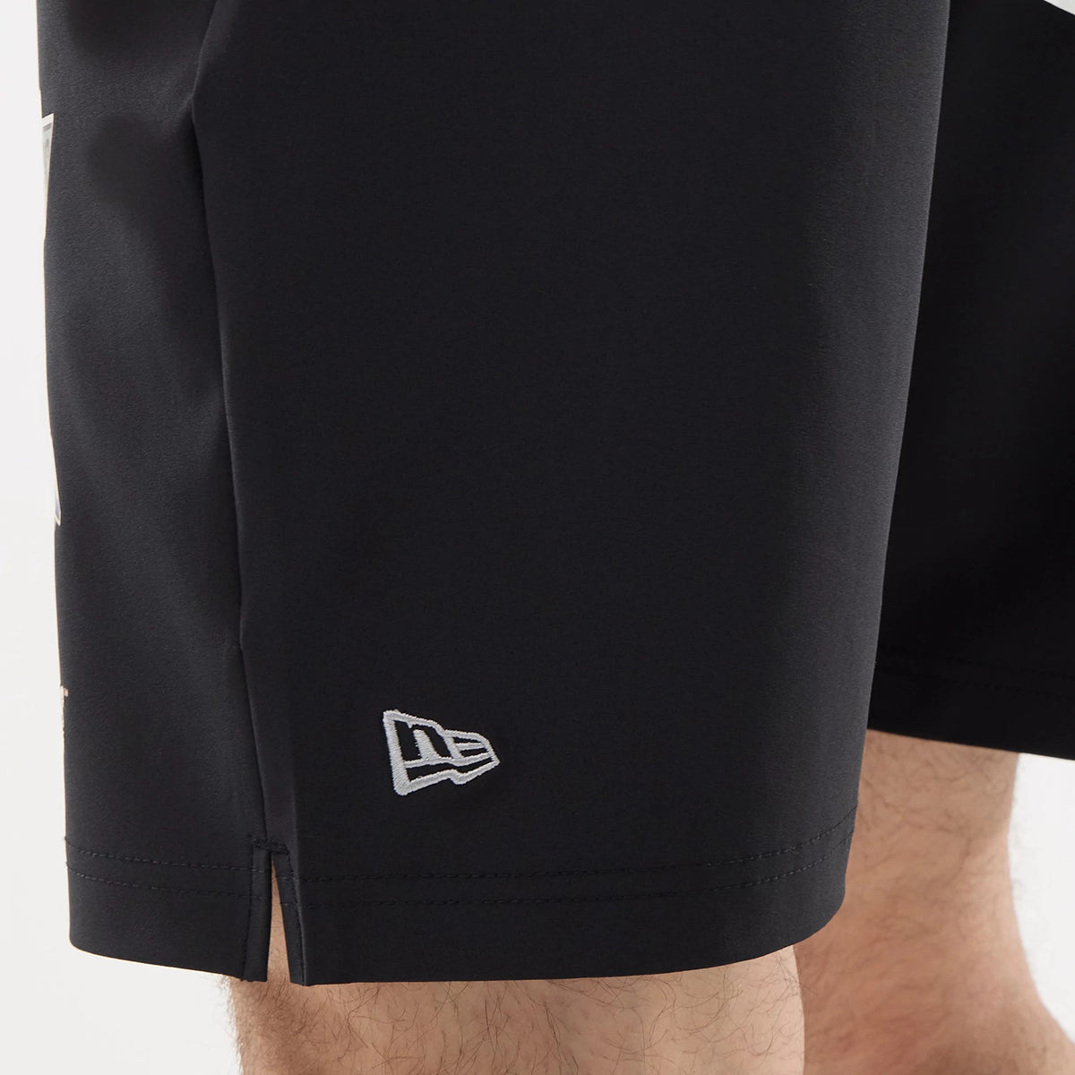 New Era LA Kings NHL Match Black Oversized Shorts, side view showing the hemline detail and split at the side, with an embroidered white New Era logo positioned near the bottom edge.