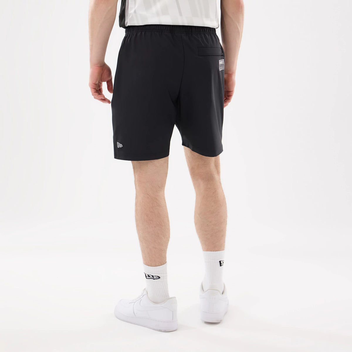 New Era LA Kings NHL Match Black Oversized Shorts, back view on a model showing the elastic waistband, a black pocket with a white embroidered New Era logo below it, and team branding on the right side.