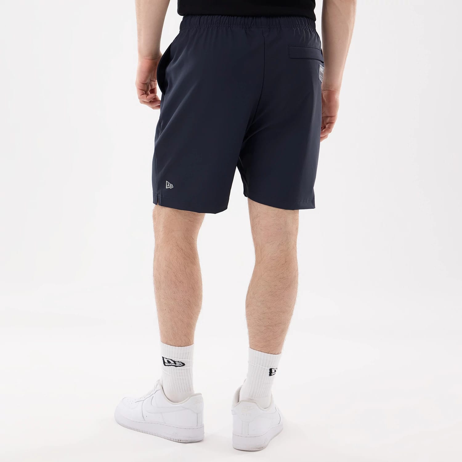 New Era New York Yankees MLB Match Navy Oversized Shorts, back view on a model wearing white trainers and socks, a small embroidered New Era logo near the hem and a single back pocket.