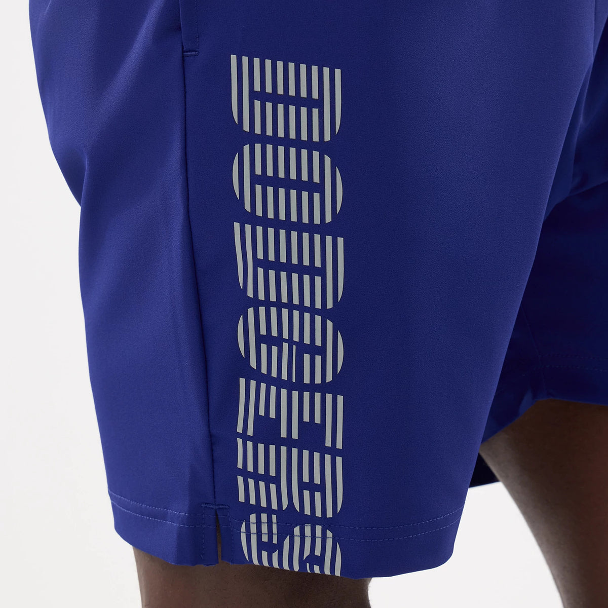 New Era LA Dodgers MLB Match Dark Blue Oversized Shorts, side view showing vertical Dodgers lettering in a light colour along the lower side of the dark blue shorts with a slit at the hem.