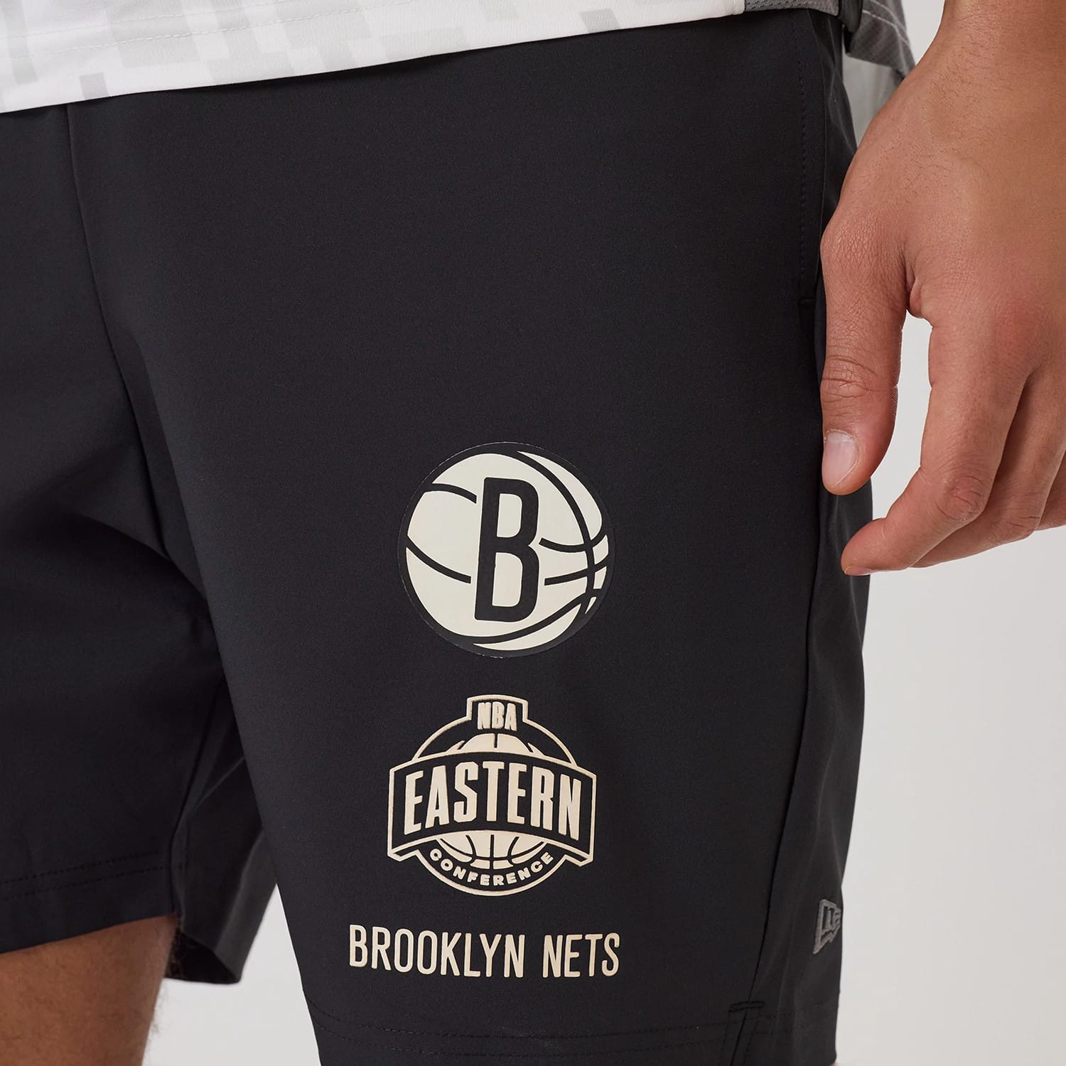 New Era Brooklyn Nets NBA Match Black Oversized Shorts, front view showing the printed Brooklyn Nets logo and NBA Eastern Conference emblem centred on the lower leg along with Brooklyn Nets lettering towards the hem.