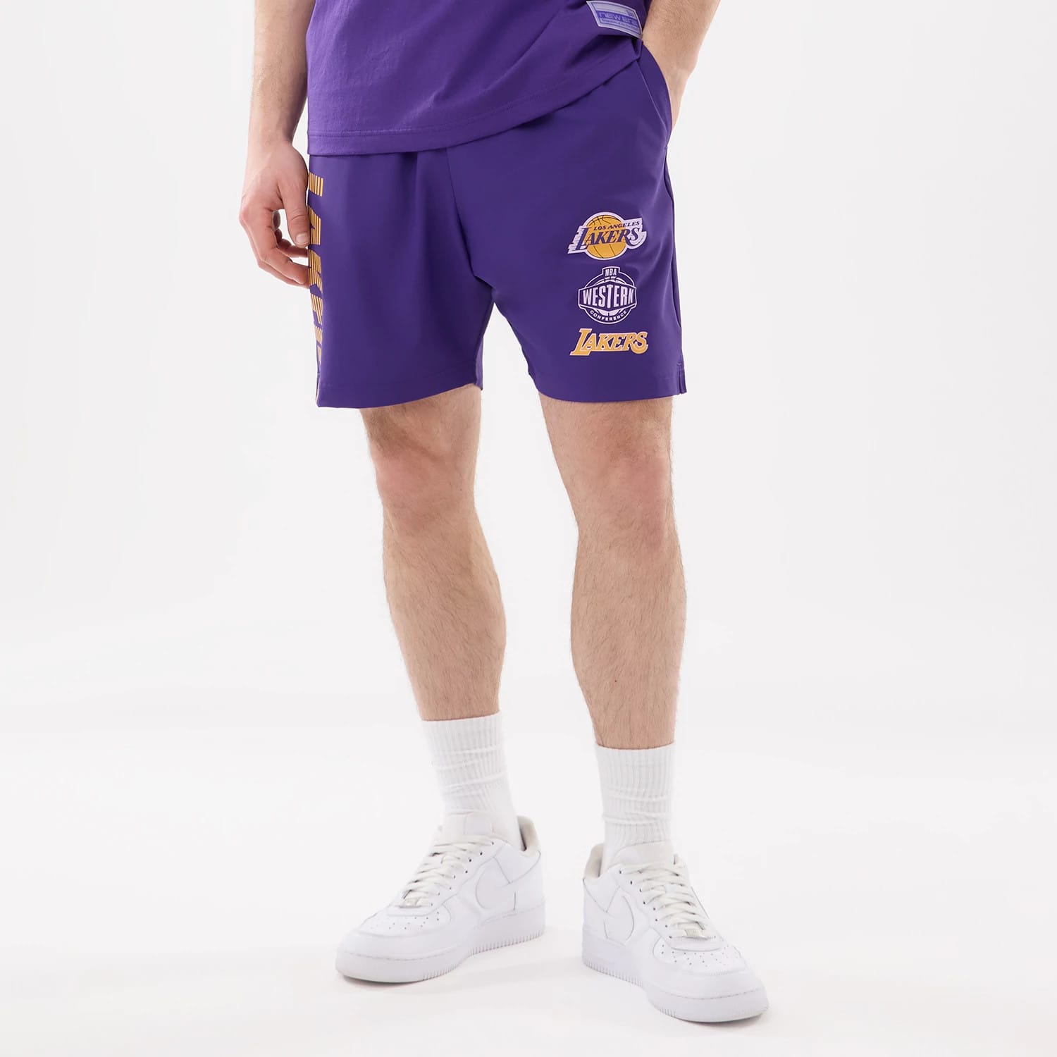 New Era LA Lakers NBA Match Purple Oversized Shorts, front view on-model showing multiple embroidered logos including the Lakers and Western Conference badges on the right leg, with Lakers lettering vertically down the left side.