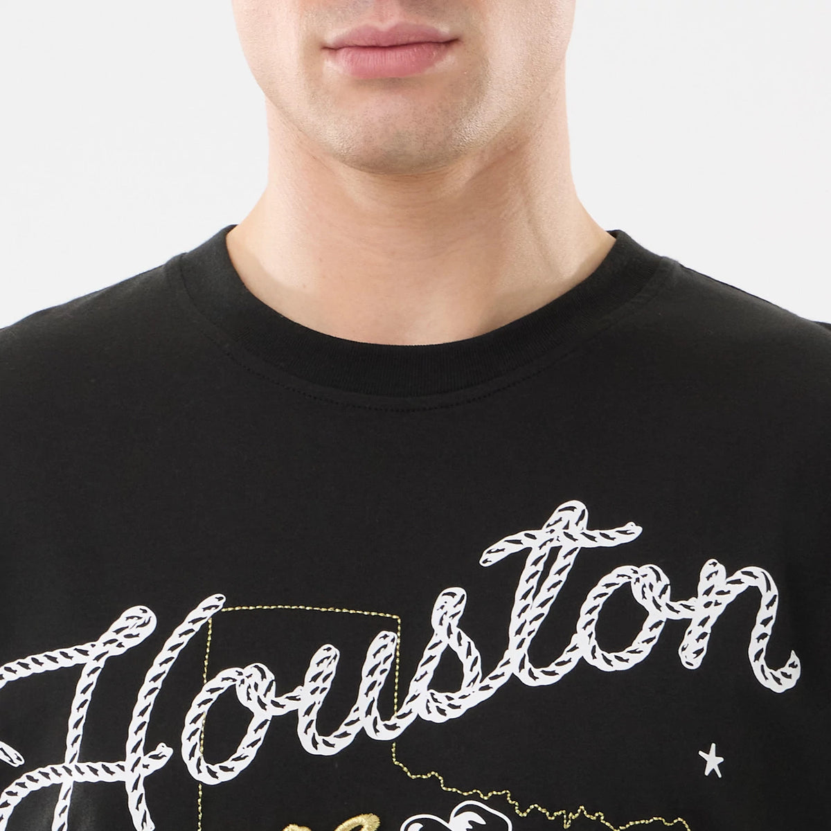 New Era Houston Astros MLB Cowboy Graphic Black T-Shirt, front view on-model showing a white rope-style Houston script across the chest with a gold outline of Texas, capturing a sporty and classic design.