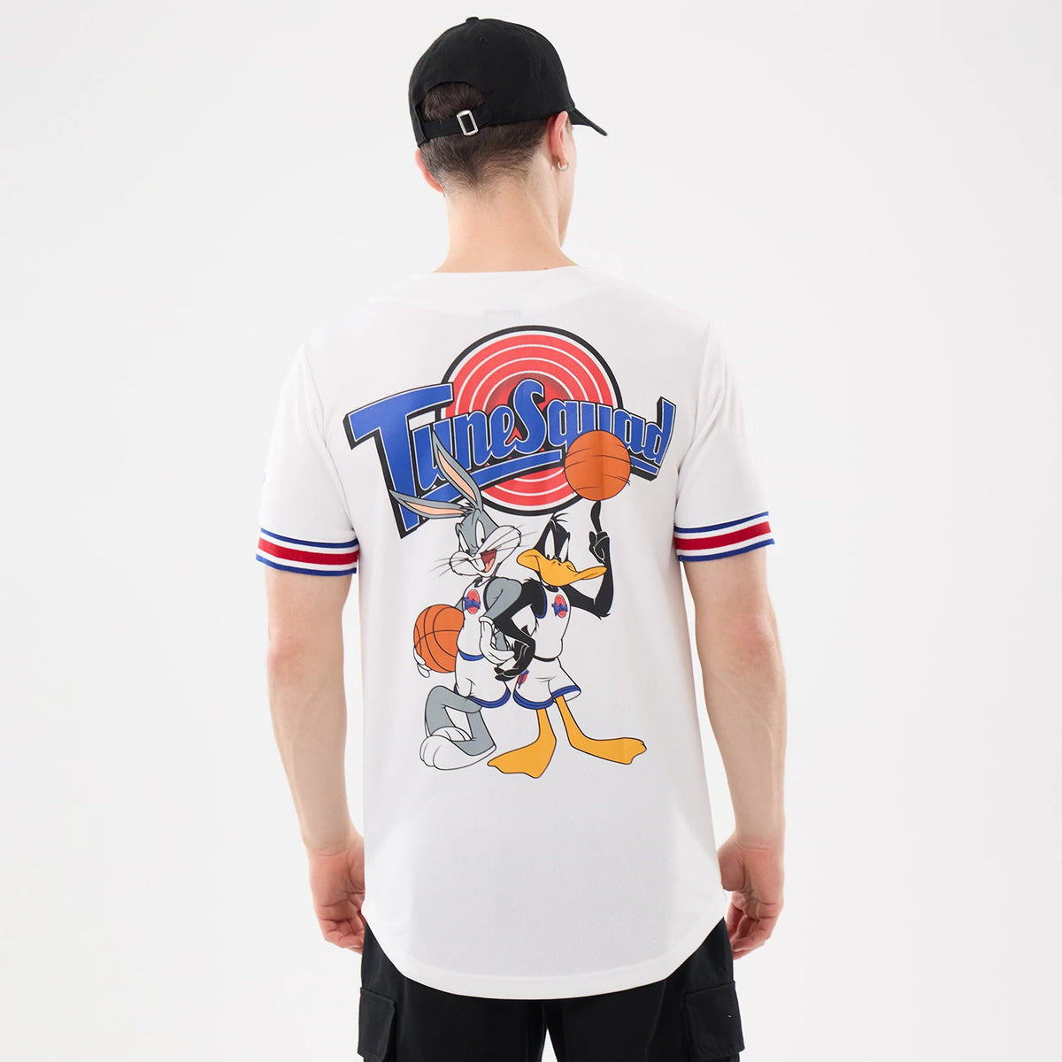 New Era Space Jam Warner Brothers Space Jam White Mesh Jersey, back view on a model with a black cap, featuring large Tune Squad lettering and Bugs Bunny and Daffy Duck graphic holding basketballs against a white mesh fabric.