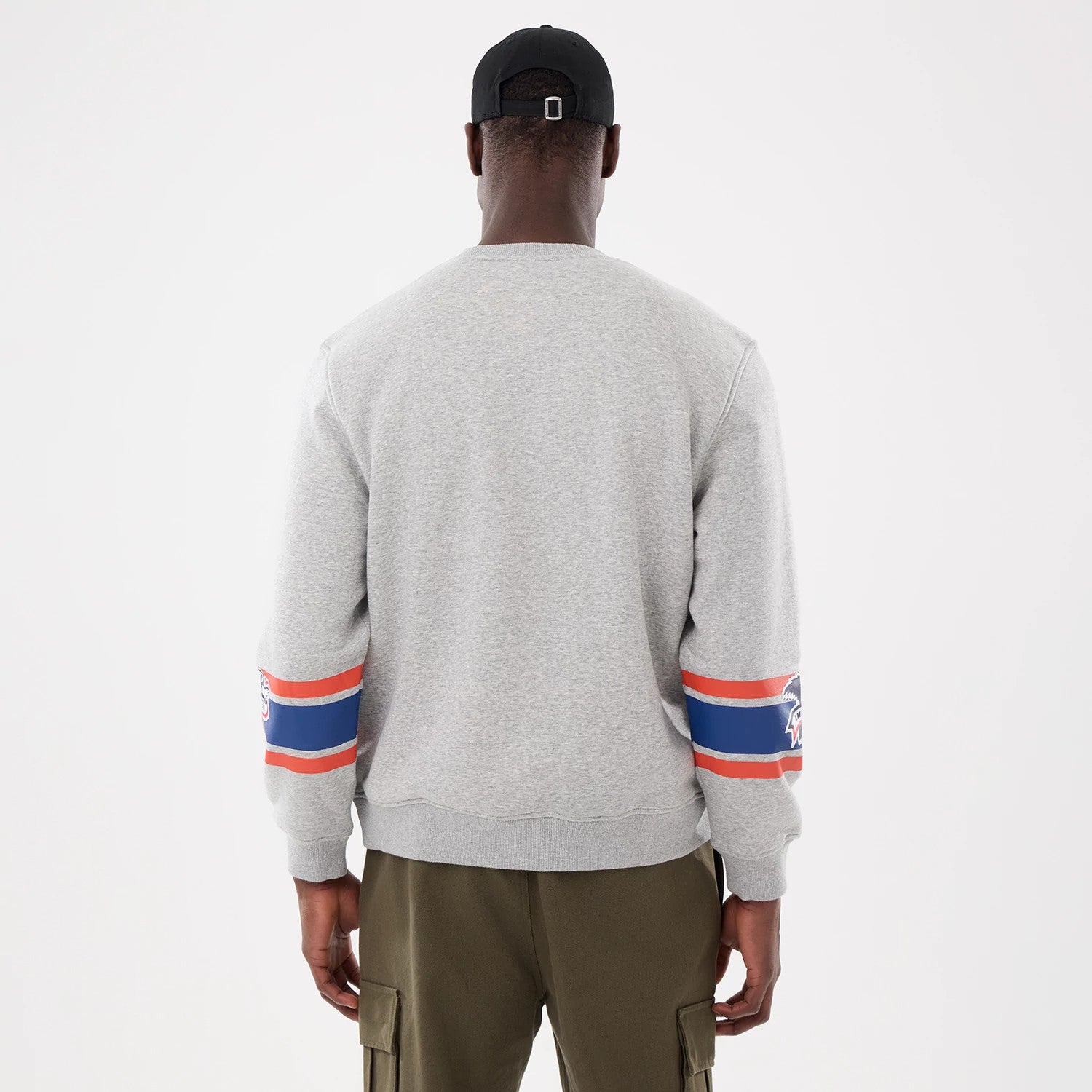 New Era Toronto Blue Jays MLB Sport Classic Grey Crew Neck Sweater, back view on a model showing the striped blue and red on the sleeves with the Blue Jays logo above the cuffs, paired with khaki cargo trousers.