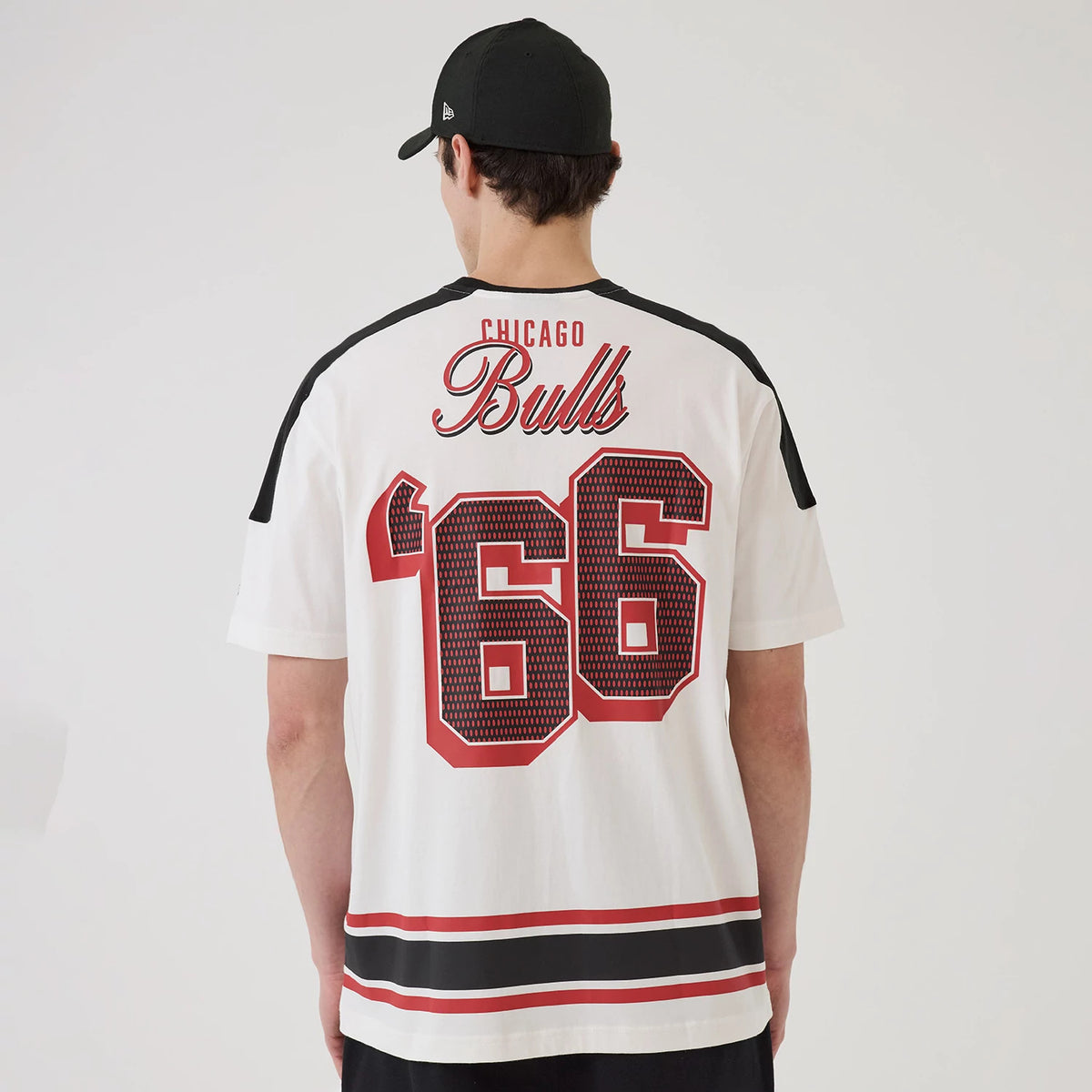 New Era Chicago Bulls NBA Sport Classic White T-Shirt, back view on a model with a plain black cap, featuring large red and black '66 numbers and Chicago Bulls lettering across the upper back, complemented by stripes across the lower section.
