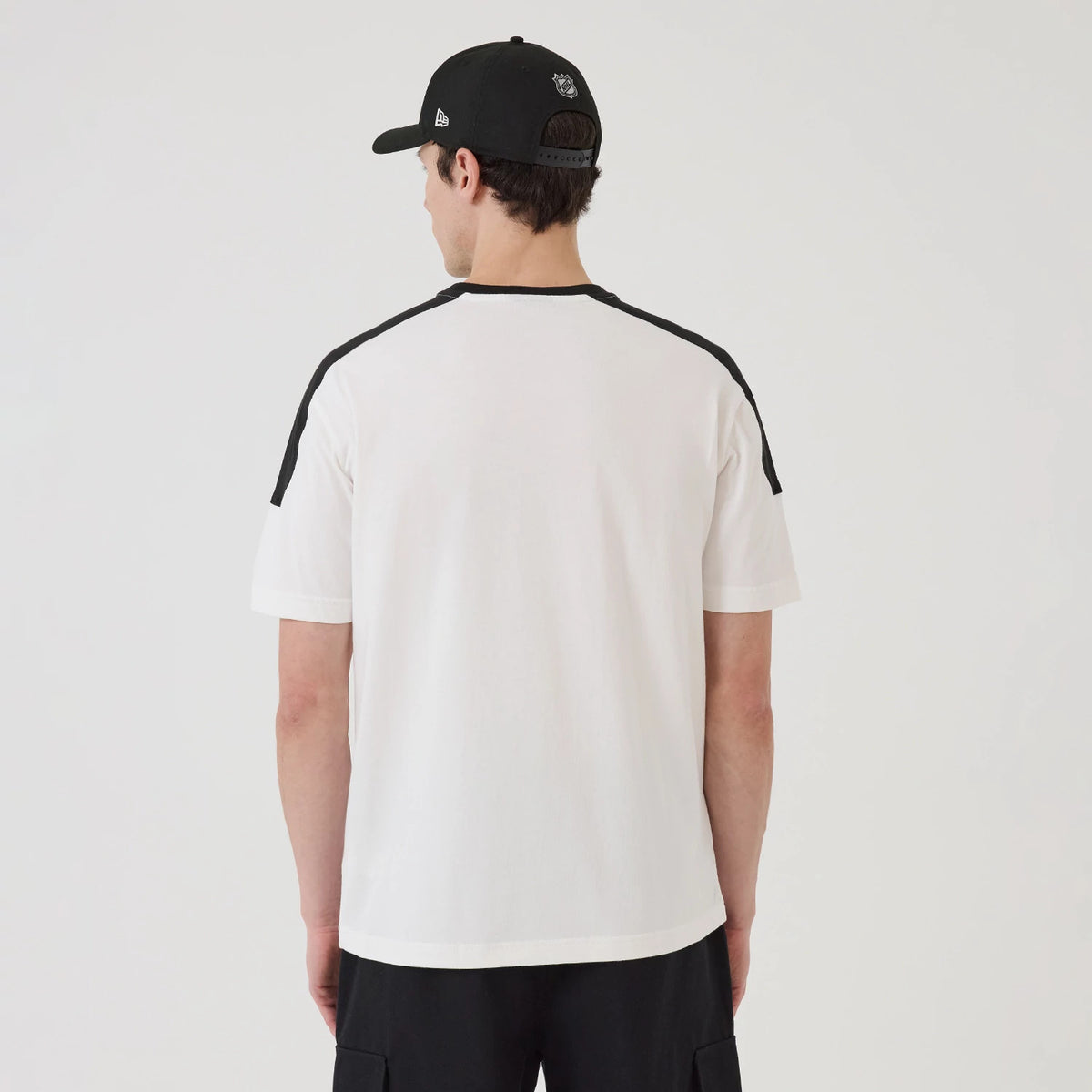 New Era LA Kings NHL Sport Classic White T-Shirt, back view on a model wearing a black cap, showing the plain white back with contrasting black stripe along the shoulders and sleeves.