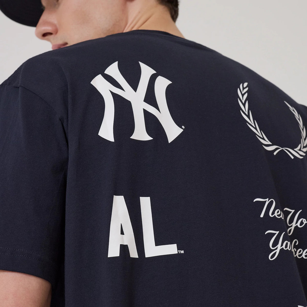 New Era New York Yankees MLB Match Navy T-Shirt, back view showing the large white printed Yankees logo near the shoulder, additional white graphics including AL lettering and decorative elements across the navy fabric.
