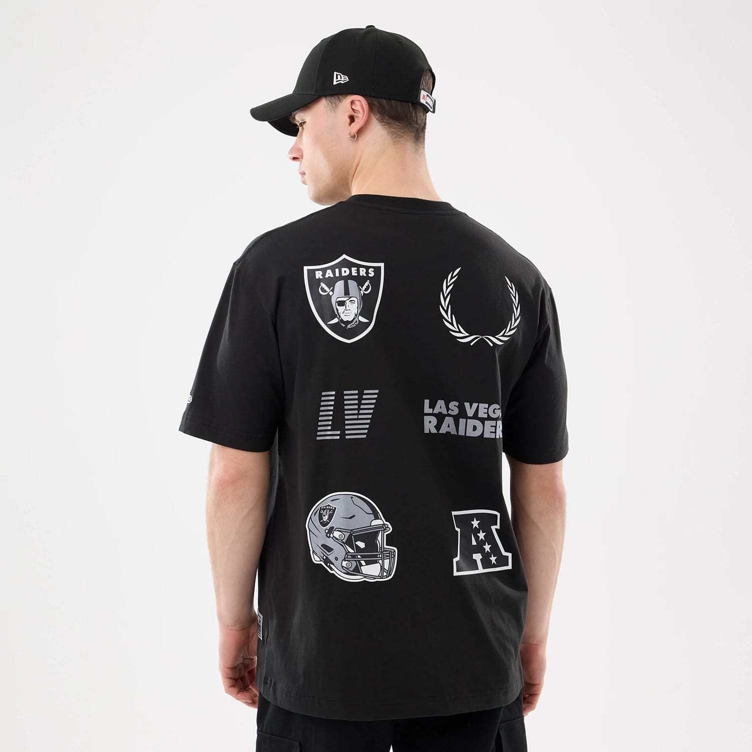 New Era Las Vegas Raiders NFL Match Black T-Shirt, back view showing large printed graphics including the Raiders shield logo, football helmet, laurels, LV lettering and AFC emblem, worn by a model with a matching black cap.