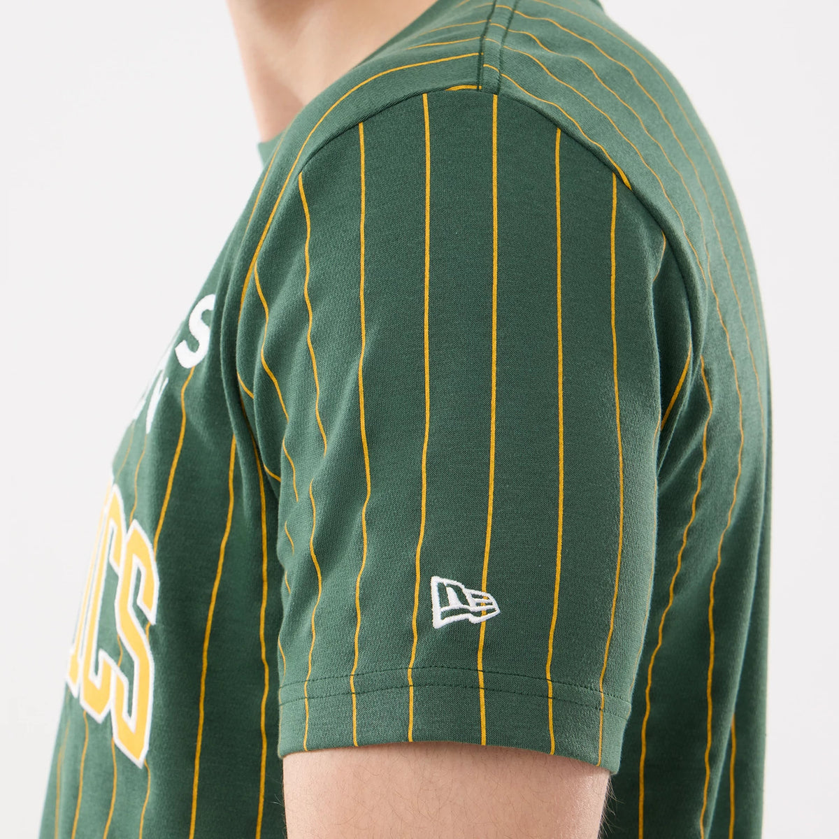 New Era Athletics MLB Pinstripe Dark Green T-Shirt, side view showing yellow pinstripes running vertically down the dark green fabric, with a white embroidered New Era logo near the hem of the short sleeve.