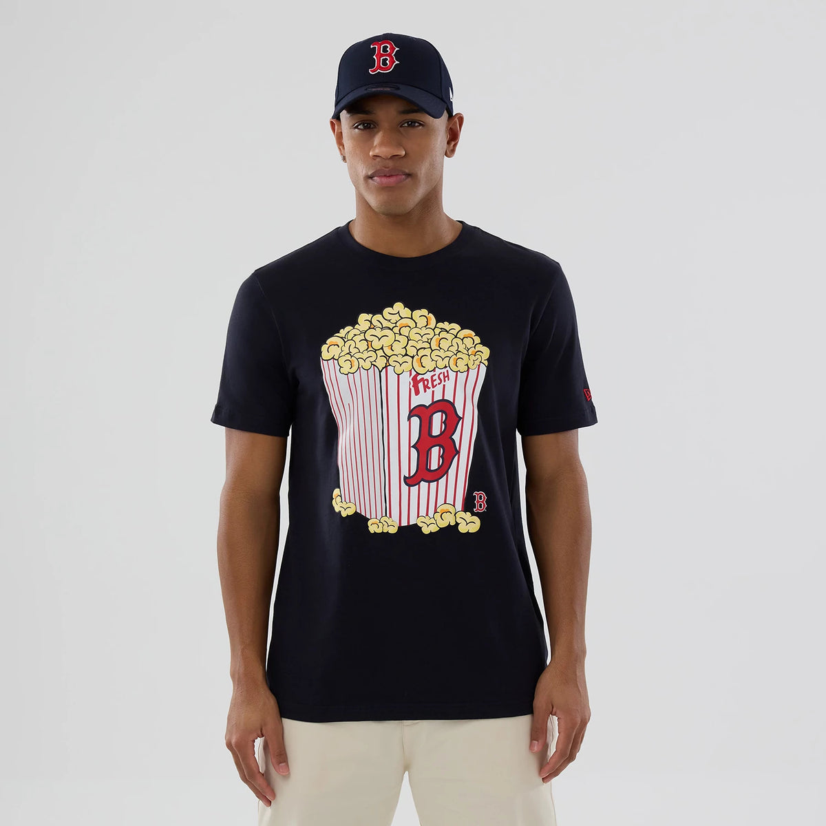 New Era Boston Red Sox MLB Popcorn Navy T-Shirt, front view on-model showing a large popcorn graphic with the Boston Red Sox B in red at the centre, a small embroidered logo on the left sleeve, styled with a matching navy cap.