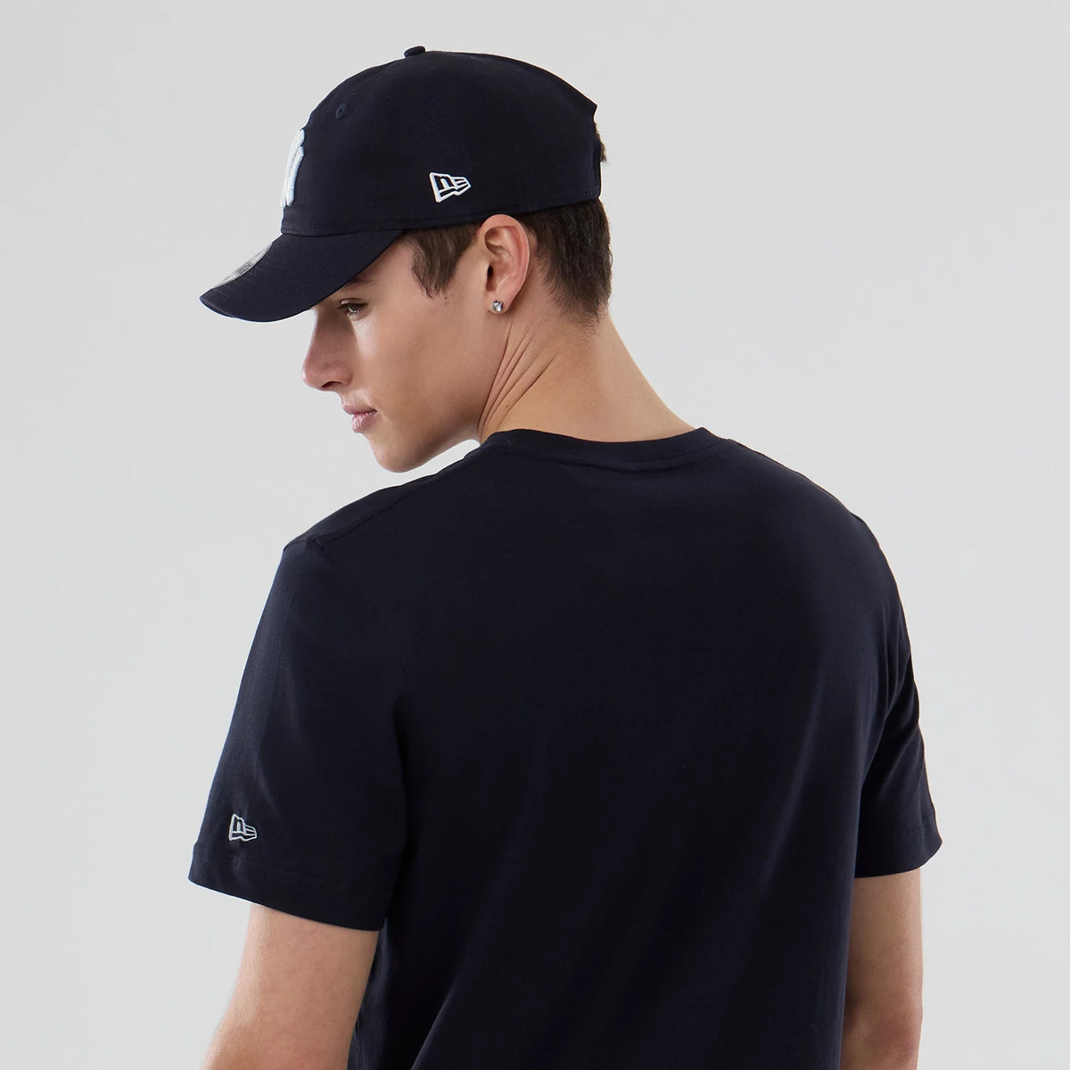 New Era New York Yankees MLB Popcorn Navy T-Shirt, back view on-model featuring the plain navy back with a small white embroidered New Era logo on the left sleeve, styled with a matching navy cap showing a side logo.