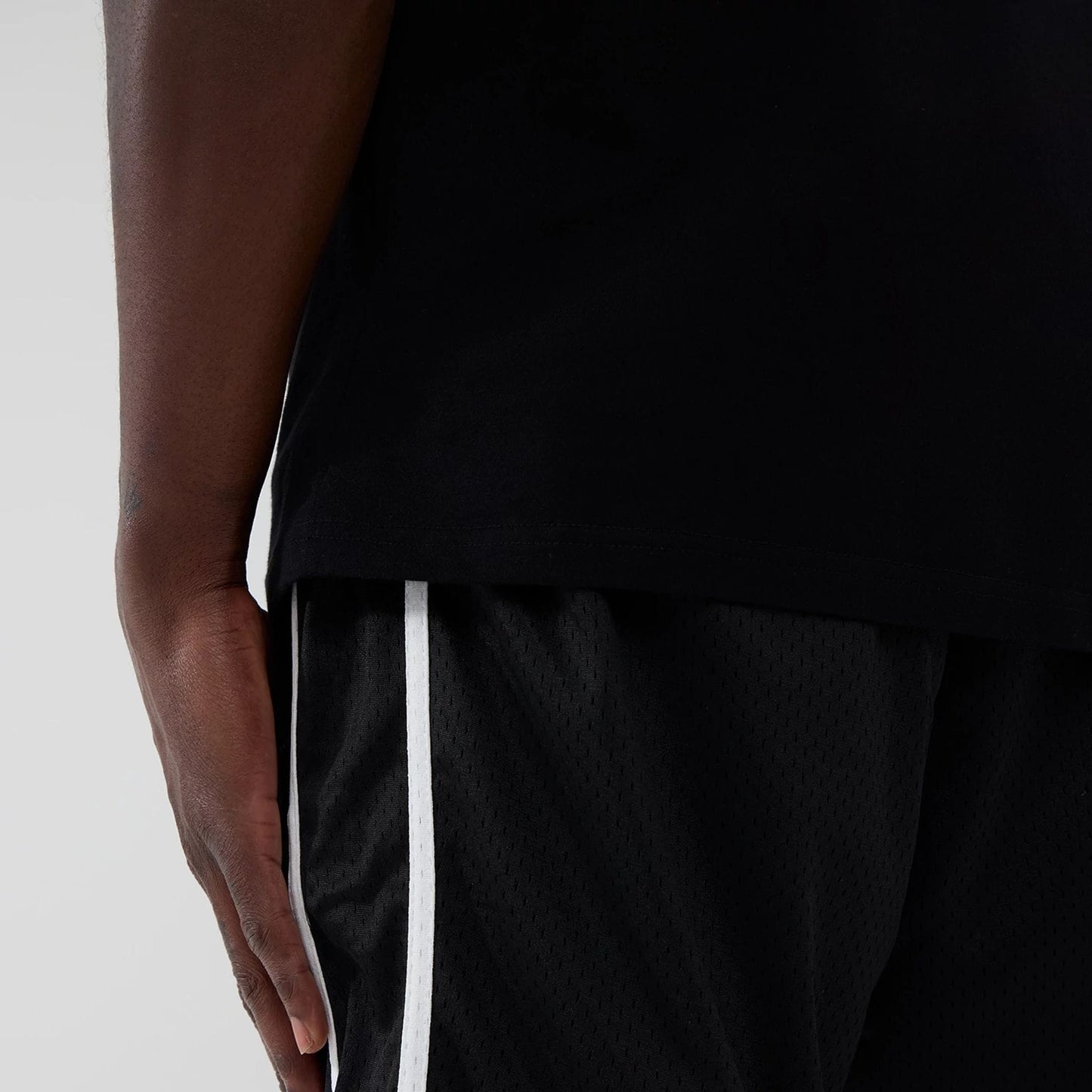 New Era Chicago Bulls NBA Black Mesh Shorts, side view showing a model wearing the shorts with white vertical piping along the sides, black mesh material, and the shorts paired with a black top.