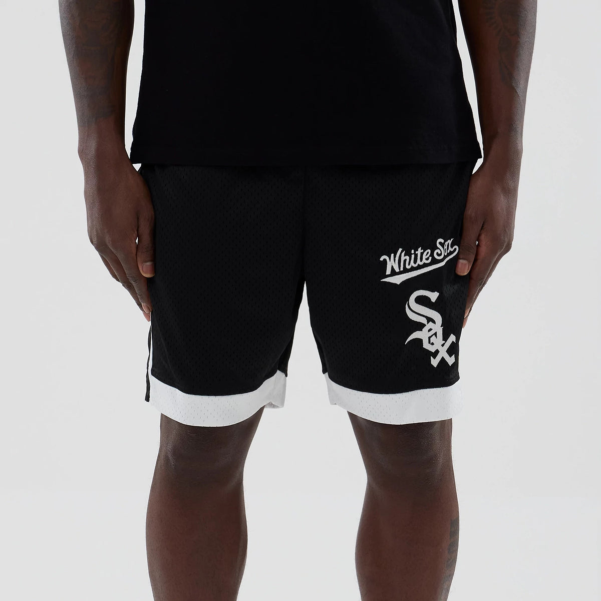 New Era Chicago White Sox MLB Black Mesh Shorts, front view on-model showing the white embroidered White Sox script and Sox logo on the left leg, contrasting white trim at the leg openings complementing the black mesh fabric.