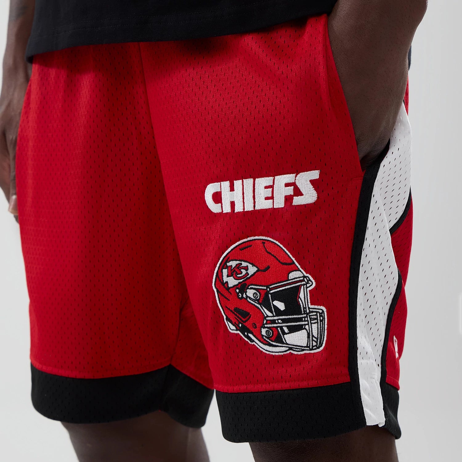 New Era Kansas City Chiefs NFL Red Mesh Shorts, side view showing the white embroidered CHIEFS lettering and a Chiefs helmet logo on the red mesh fabric with black trim and a white mesh panel down the side.