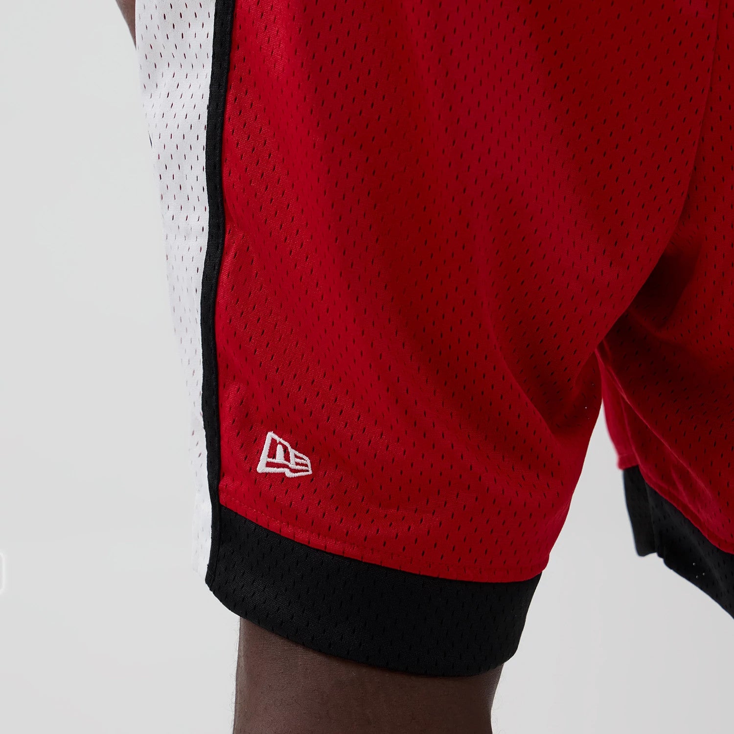 New Era Kansas City Chiefs NFL Red Mesh Shorts, three-quarter view showing the red mesh fabric with a contrasting white side stripe and black hem, featuring a white embroidered New Era logo near the bottom edge.