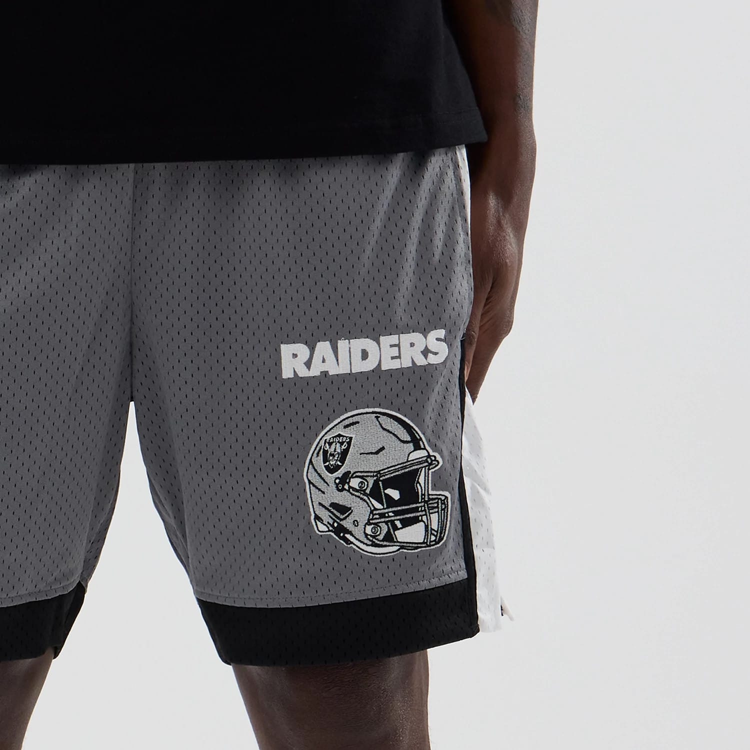 New Era Las Vegas Raiders NFL Grey Mesh Shorts, front view showing the white embroidered Raiders lettering and helmet graphic on the left leg, set against the grey mesh fabric with black trim at the hem.