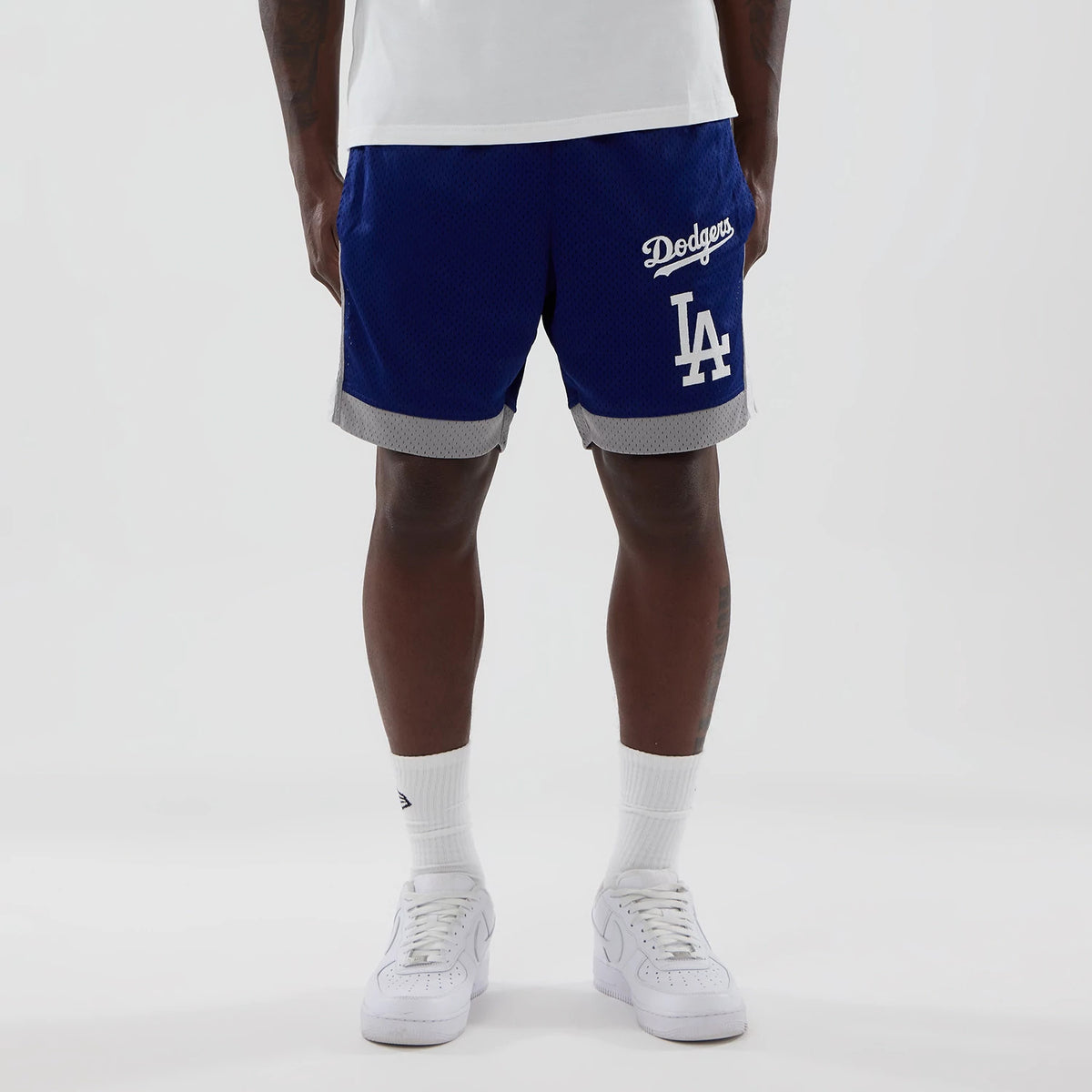 New Era LA Dodgers MLB Dark Blue Mesh Shorts, front view on-model showing the dark blue mesh with grey trim, white embroidered Dodgers script on the right leg, and large LA lettering on the left leg.