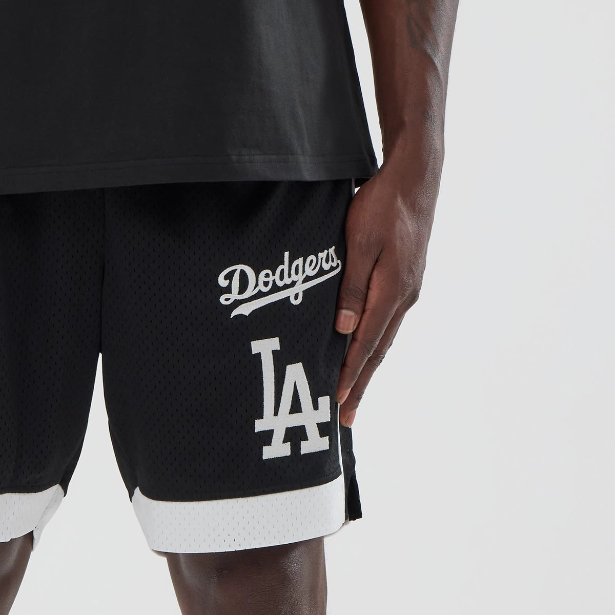 New Era LA Dodgers MLB Black Mesh Shorts, front view showing the black mesh fabric with white embroidered Dodgers script logo near the hip and large LA lettering on one leg, with white trim at the hem.