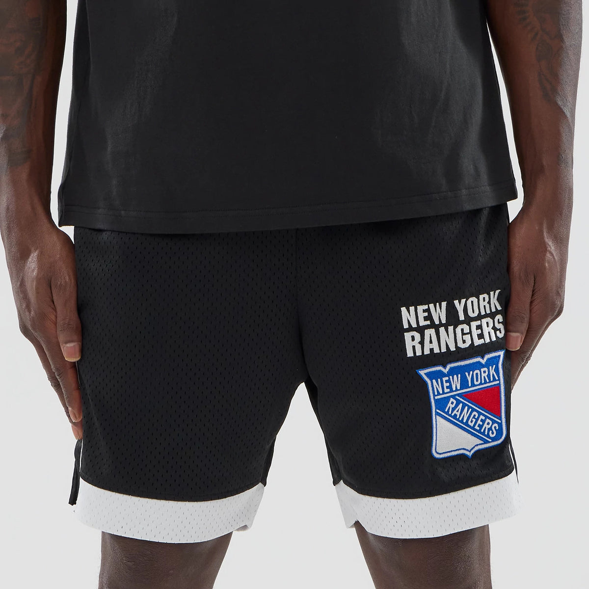 New Era New York Rangers NHL Black Mesh Shorts, front view showing the embroidered New York Rangers logo and text on the left leg above the white mesh trim, styled with a plain black tee.