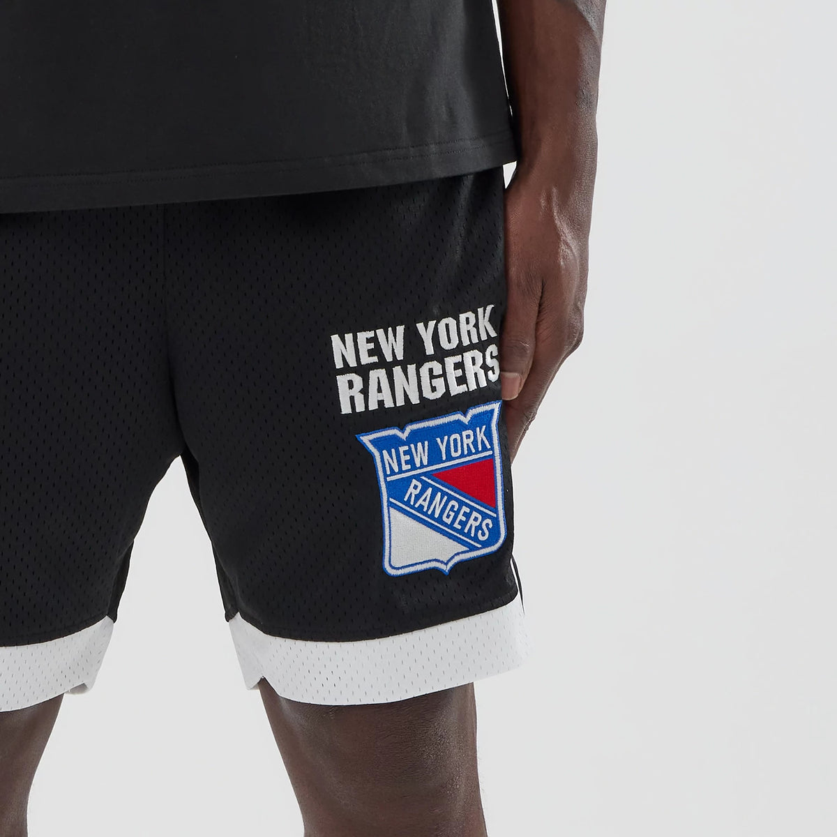 New Era New York Rangers NHL Black Mesh Shorts, front view displaying the embroidered New York Rangers logo and name prominently on the right leg, with white trim at the hem and a mesh texture throughout.