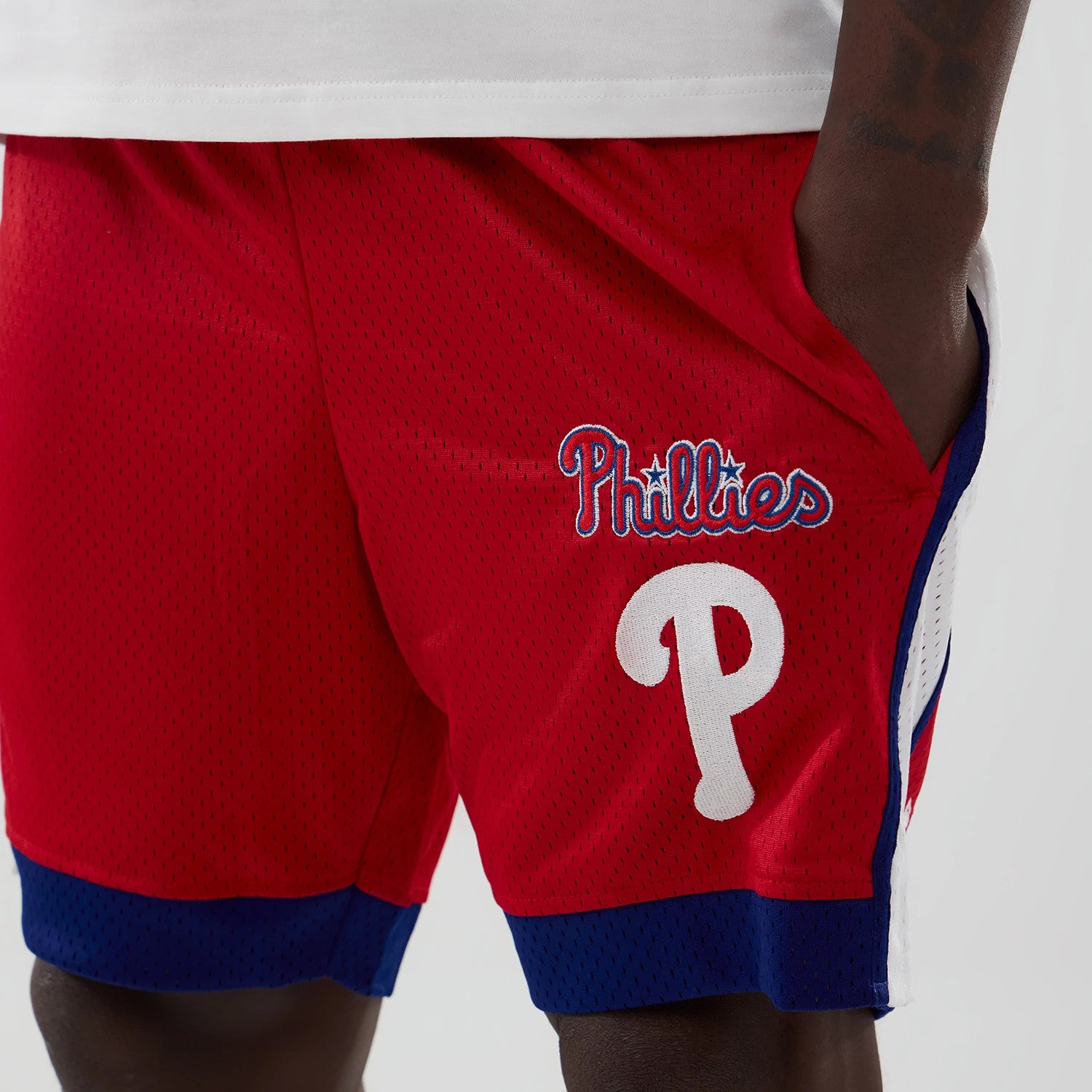 New Era Philadelphia Phillies MLB Red Mesh Shorts, front view showing the white embroidered P logo below the waistband, Phillies script in blue and white on the right leg and blue trim at the hem.