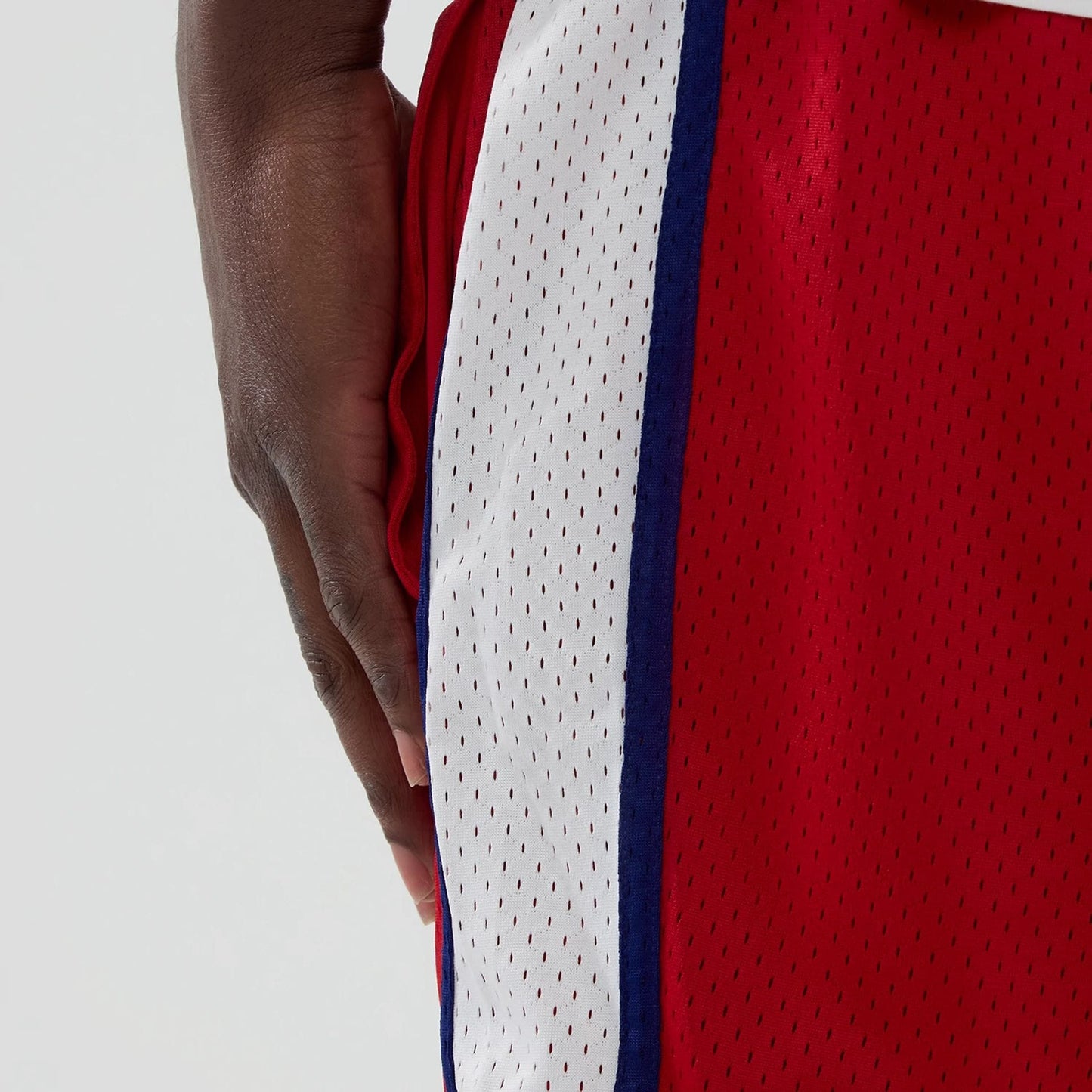 New Era Philadelphia Phillies MLB Red Mesh Shorts, side view showing the red mesh fabric with a vertical white and blue stripe on the side, emphasised by small perforations along the entire length.