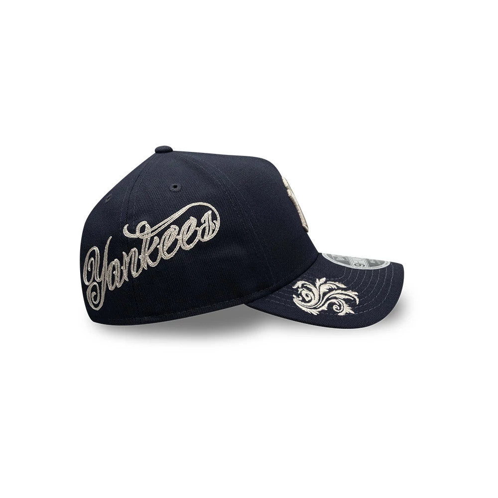 New York Yankees MLB Script Navy New Era 9FORTY M-Crown A-Frame Adjustable Cap, side view showing raised beige Yankees script embroidered on the navy crown and ornate embroidery on the navy curved visor, with a 9FORTY size sticker.
