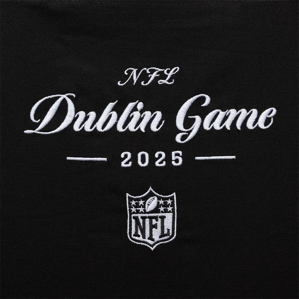 New Era Shield Logo NFL Dublin Game 2025 Black Tote Bag, front view showing the white embroidered lettering Dublin Game 2025 beneath NFL and above the shield logo with stars and a football, all centred on the black surface.