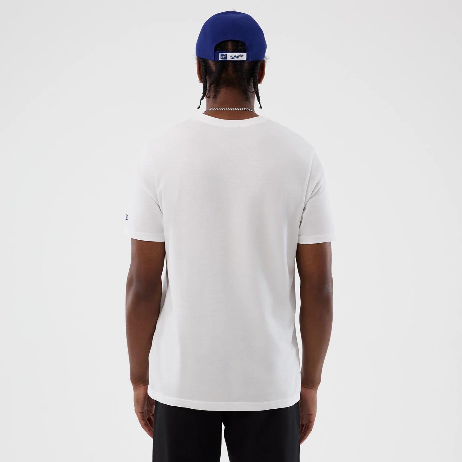 New Era LA Dodgers MLB Back To School White T-Shirt, back view showing the plain white rear without graphics, short sleeves with a small embroidered New Era logo on the left sleeve, paired with a blue cap from the back.
