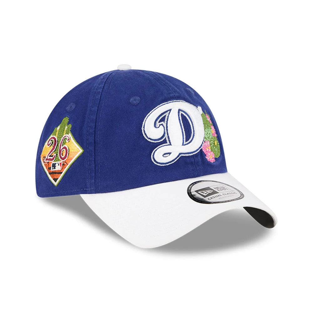 LA Dodgers MLB Spring Training 2026 Dark Blue New Era Casual Classic Adjustable Cap, three-quarter view showing a white embroidered D with floral accents on the blue crown, a number 26 patch on the side, and a white curved visor with a size sticker.