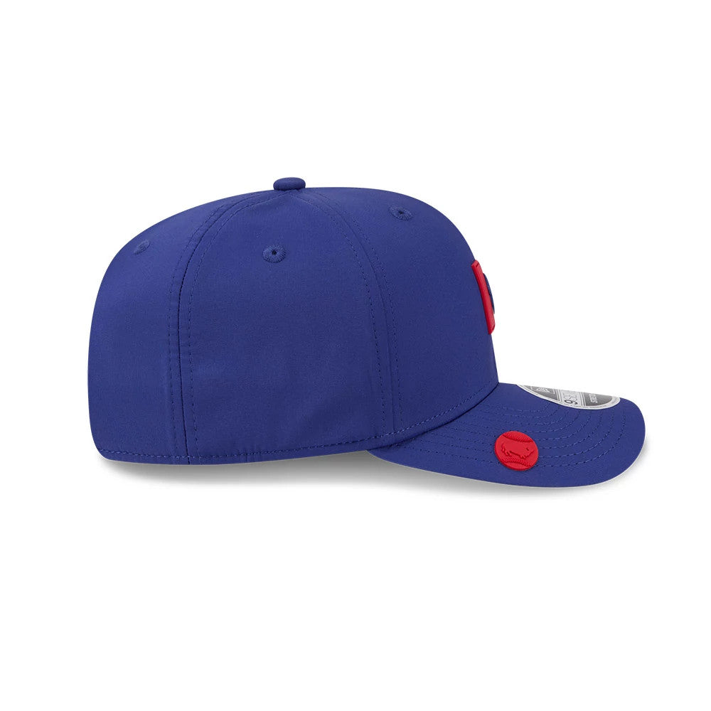 Buffalo Bisons MiLB Clubhouse Dark Blue New Era 9SEVENTY Stretch Snap Adjustable Cap, side view showing the blue structured crown with matching eyelets, and a curved visor featuring a red side logo and a 9SEVENTY size sticker.