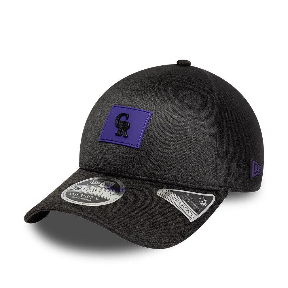 Colorado Rockies MLB Clubhouse Black New Era 39THIRTY Infinity Stretch Fit Cap, three-quarter view showing a raised black and purple patch on the front, curved black visor with multiple stickers, and purple New Era flag logo on the left side.