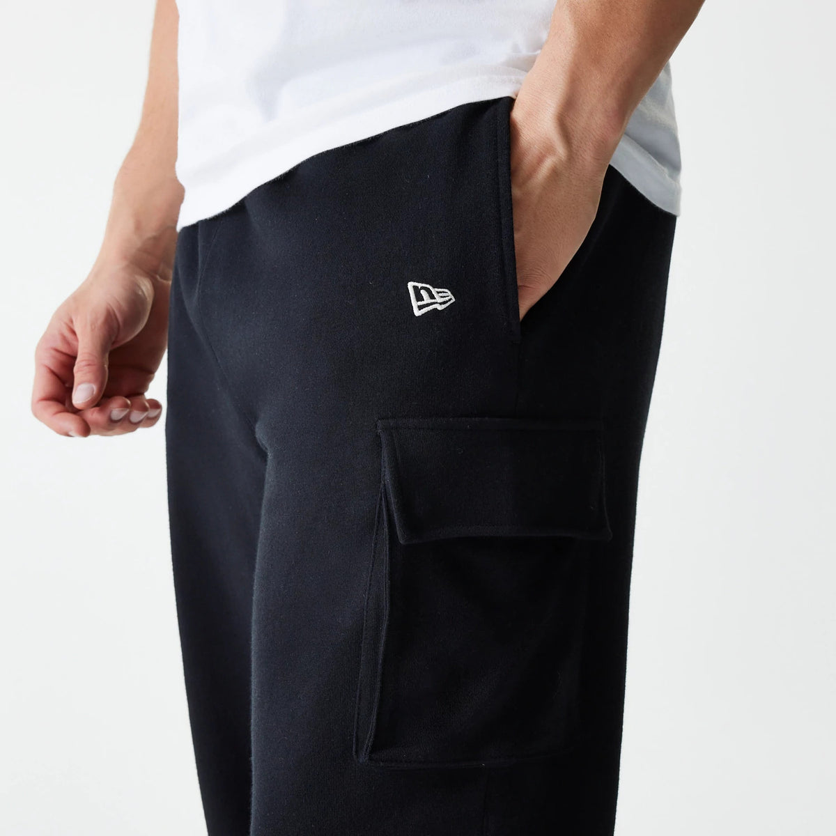 New Era Black Cargo Joggers, close-up on a model showing the embroidered New Era flag logo near the pocket and a spacious cargo pocket on the side, with the model’s hand resting in the hip pocket.