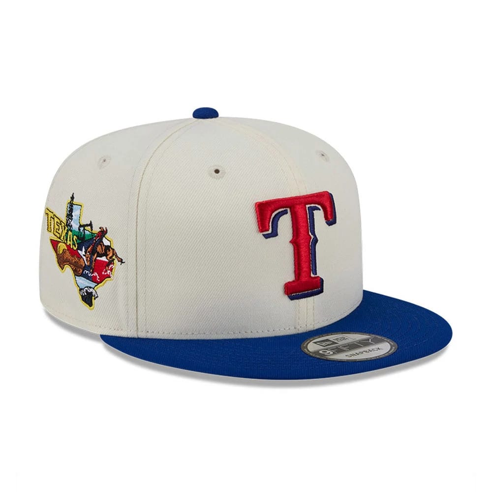 Texas Rangers MLB Localized White New Era 9FIFTY Snapback Adjustable Cap, three-quarter view showing raised red and blue embroidered T logo on the front panel and a colourful Texas-themed graphic on the right side, with a blue flat visor.