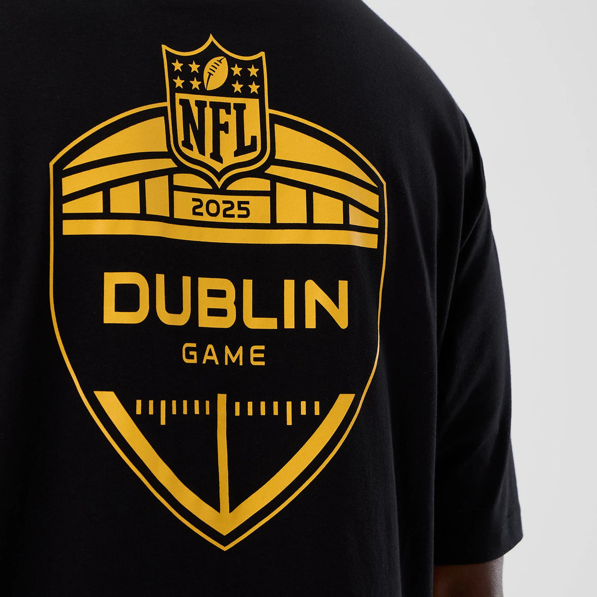 New Era Pittsburgh Steelers NFL International Series Games Black Oversized T-Shirt, back view showing a large yellow printed NFL 2025 Dublin Game graphic centred on the black fabric, with geometric shapes and lettering.