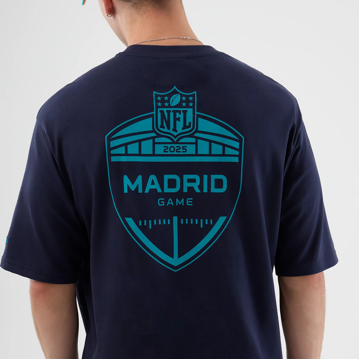 New Era Miami Dolphins NFL International Series Games Navy Oversized T-Shirt, back view showing a large teal NFL Madrid Game 2025 graphic dominating the upper back, worn by a model in a casual style.