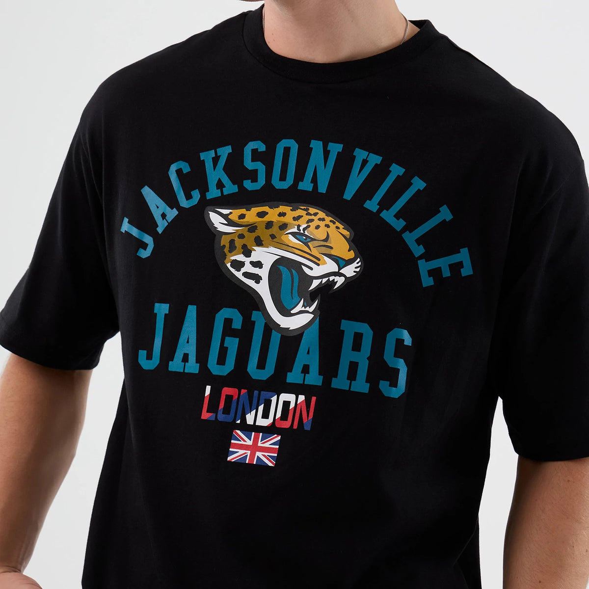 New Era Jaguars NFL International Series Games London Black Oversized T-Shirt, front view on-model showing the large printed Jacksonville Jaguars logo with teal lettering, red and white London text underneath.