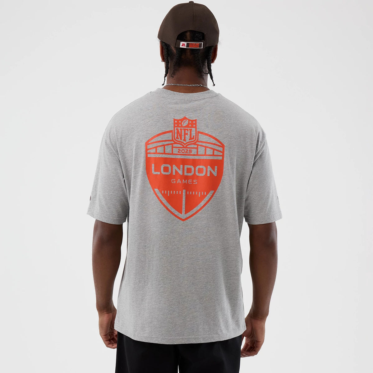 New Era Cleveland Browns NFL International Series Games Grey Oversized T-Shirt, back view on a model showing a large orange NFL London Games 2023 graphic across the shoulders on the light grey fabric with short sleeves.