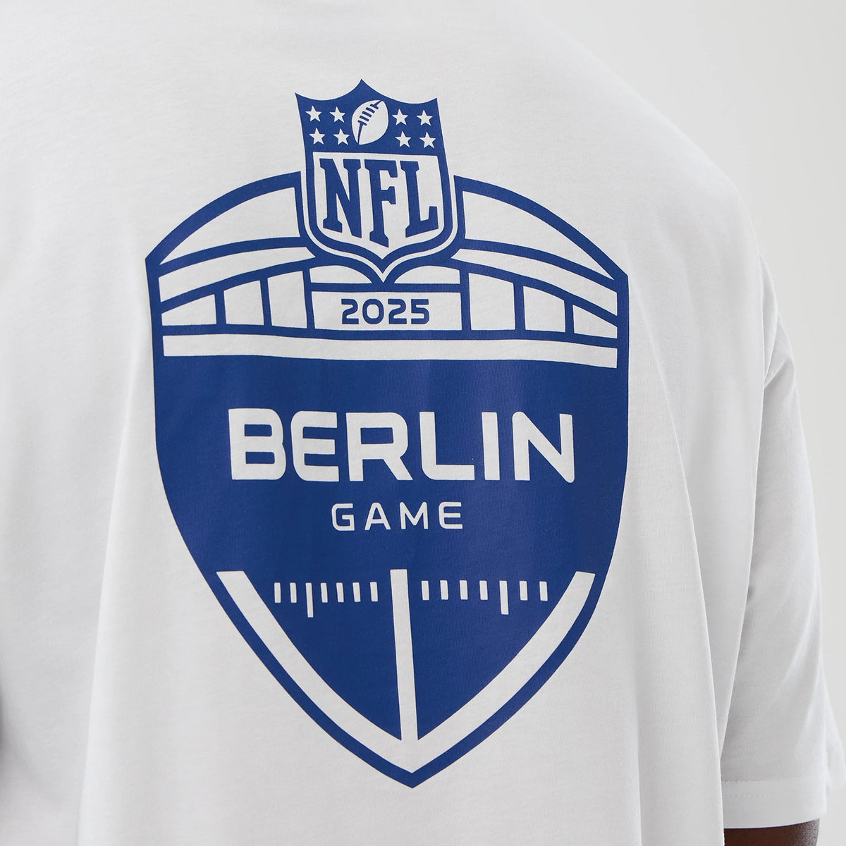 New Era Indianapolis Colts NFL International Series Games White Oversized T-Shirt, back view showing a large printed blue NFL logo above Berlin Game lettering on the white fabric, worn by a model displaying the design.