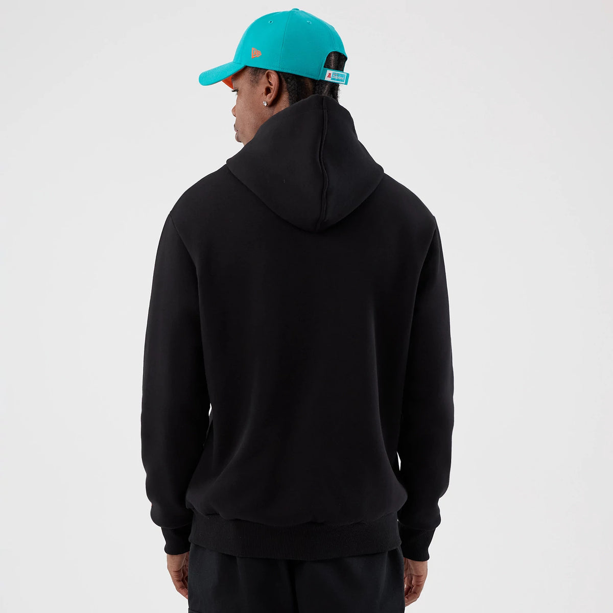 New Era Dolphins NFL International Series Games Patch Black Pullover Hoodie, back view on-model displaying a plain black design with a relaxed fit, complemented by a teal cap featuring an embroidered logo on the side.