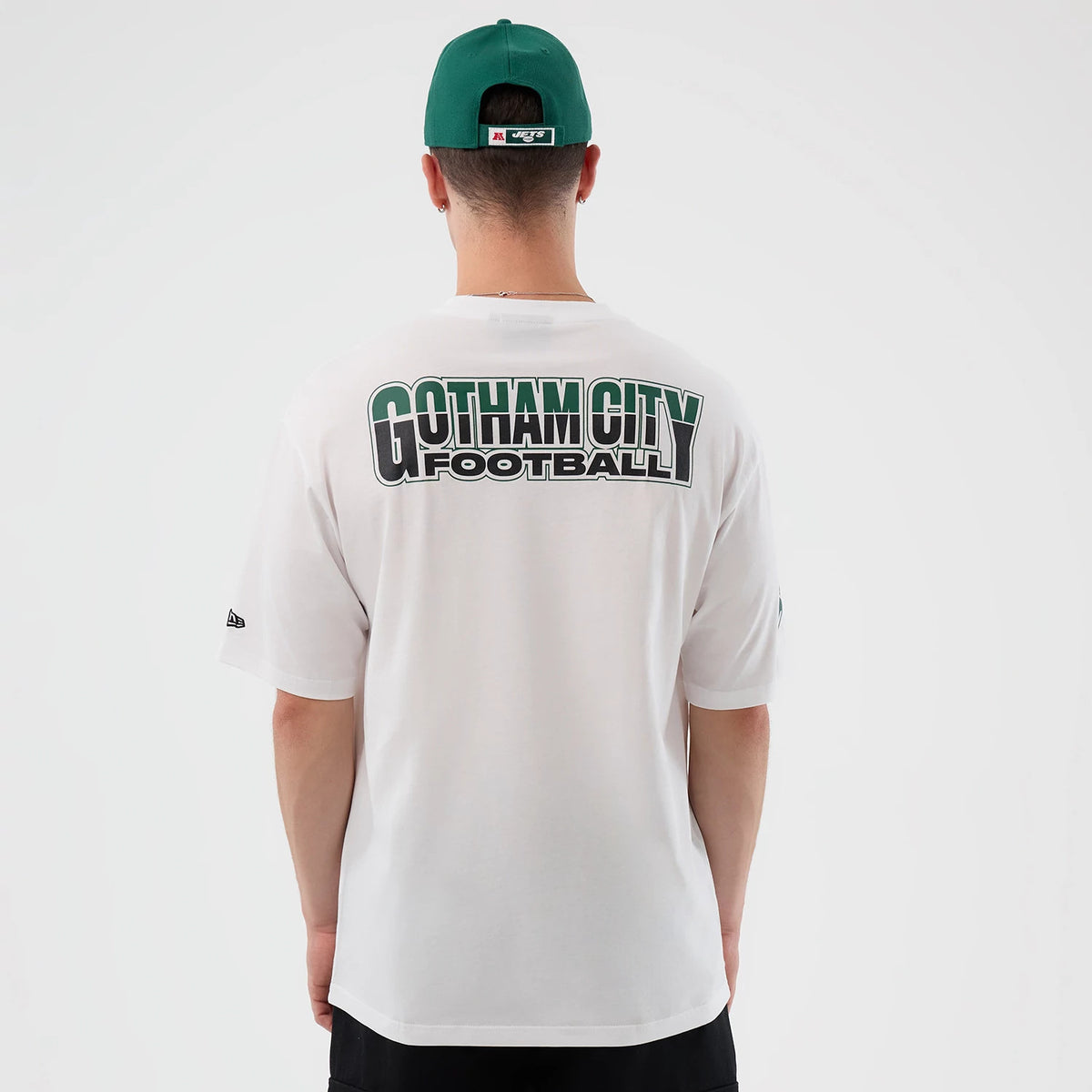 New Era New York Jets NFL International Series Games White Oversized T-Shirt, back view on-model featuring large Gotham City Football lettering across the upper back, with a small embroidered New Era logo on the left sleeve.