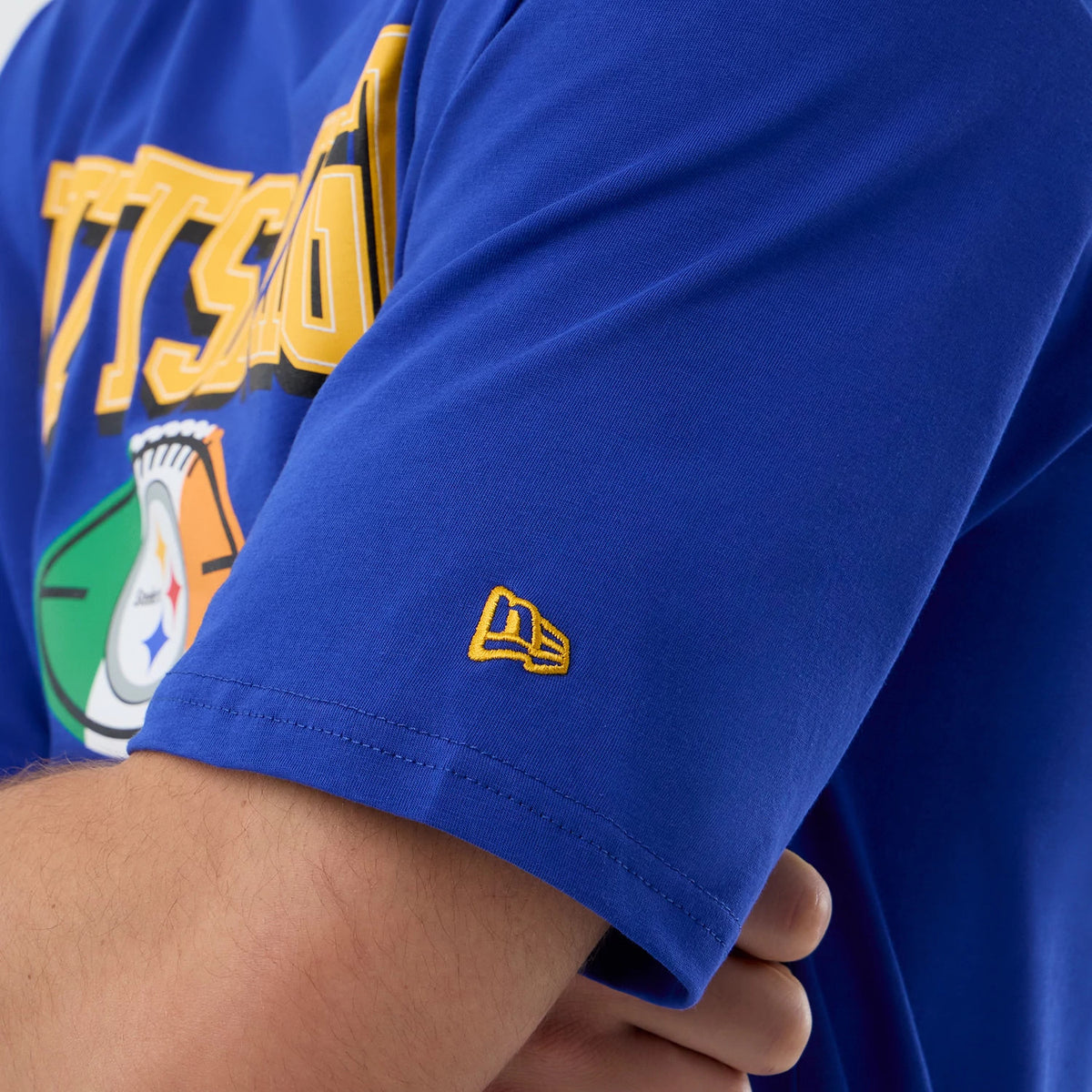 New Era Pittsburgh Steelers NFL International Series Games Blue Oversized T-Shirt, three-quarter view showing the yellow embroidered New Era logo on the left sleeve and front graphics including the Pittsburgh Steelers emblem and yellow text.
