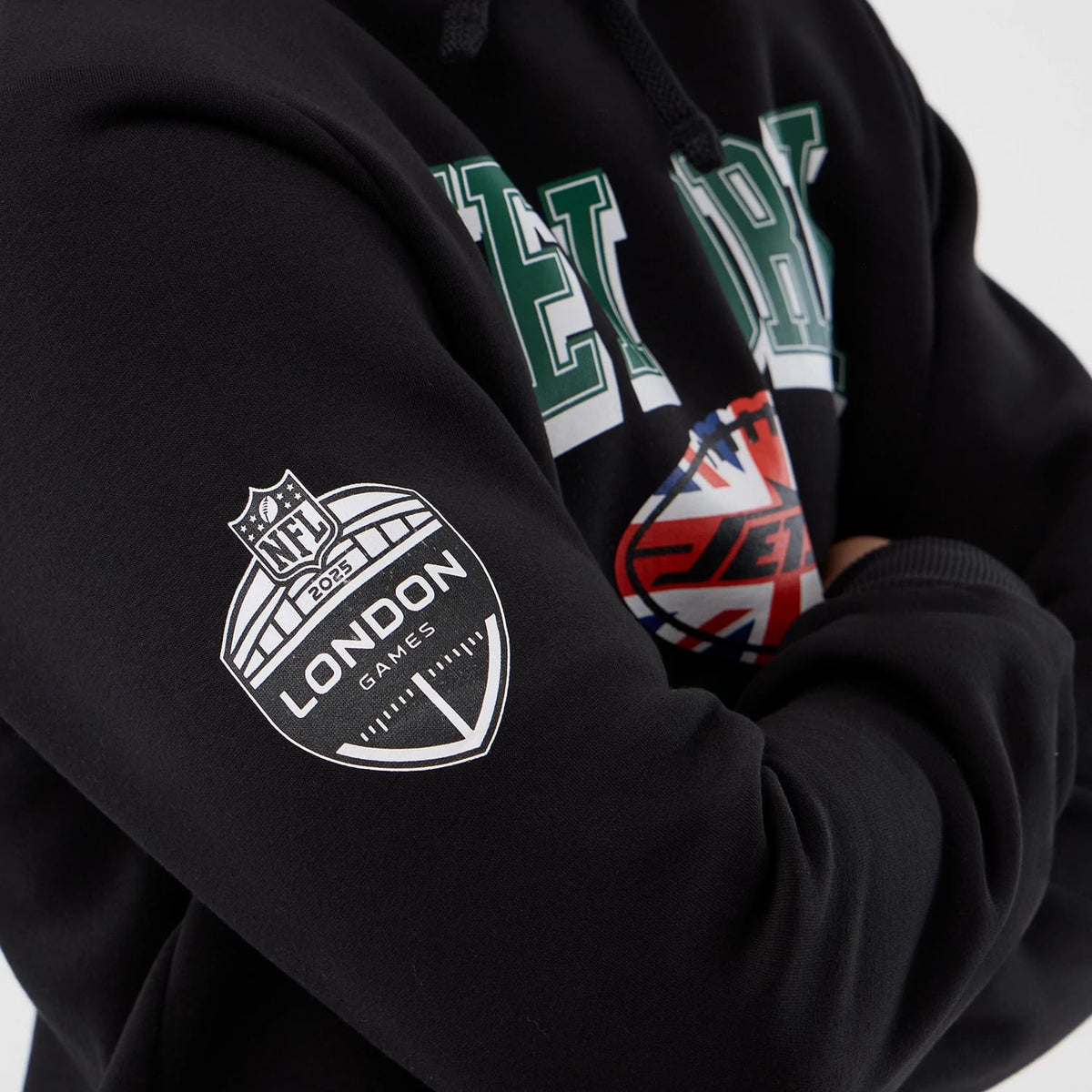 New Era New York Jets NFL International Series Games Black Pullover Hoodie, front view showing green and white New York lettering on the chest, UK flag and Jets logo underneath, with a printed NFL London Games emblem on the right sleeve.
