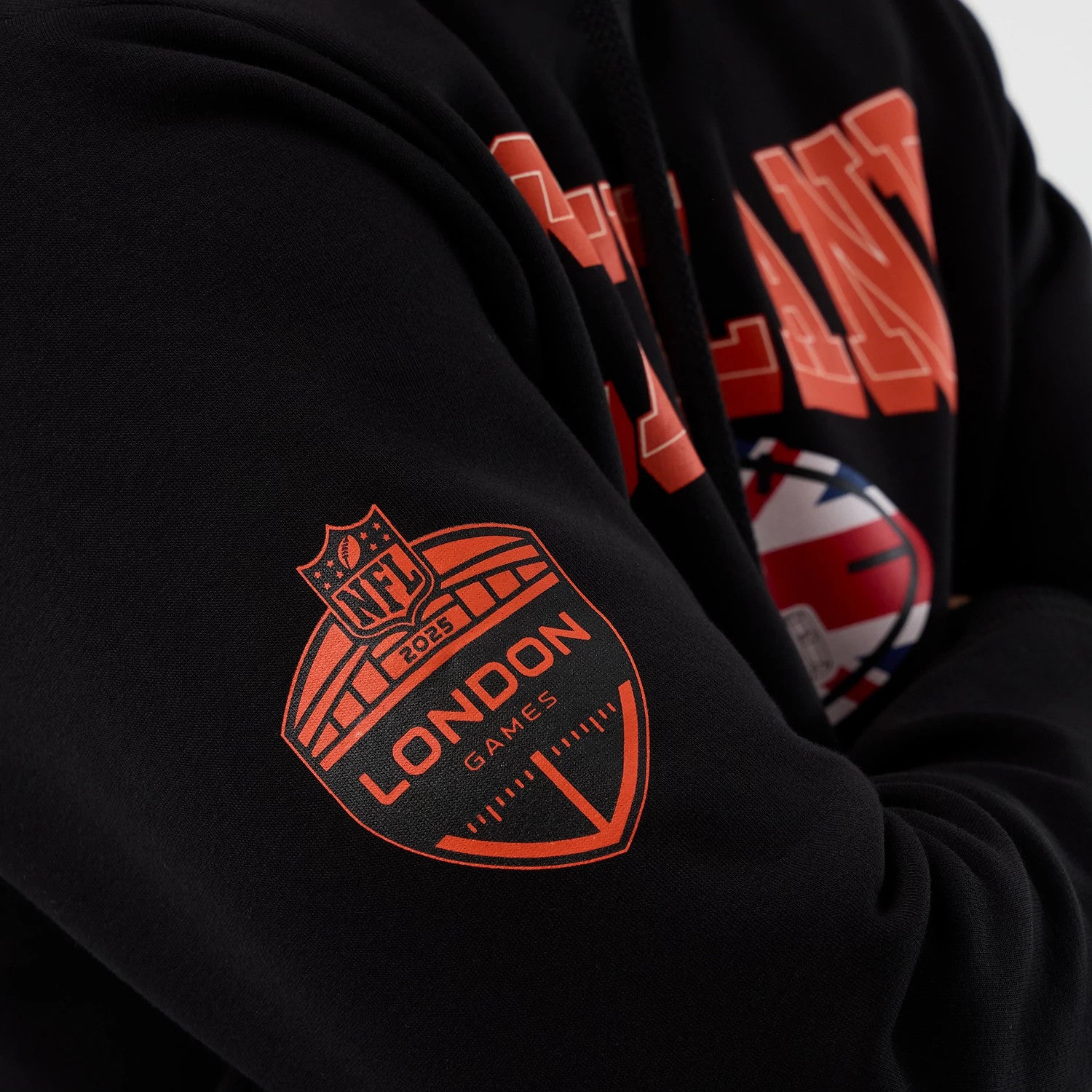 New Era Cleveland Browns NFL International Series Games Black Pullover Hoodie, front view highlighting orange lettering across the chest and an orange printed London Games emblem on the sleeve, with a close-up on the detailed design.