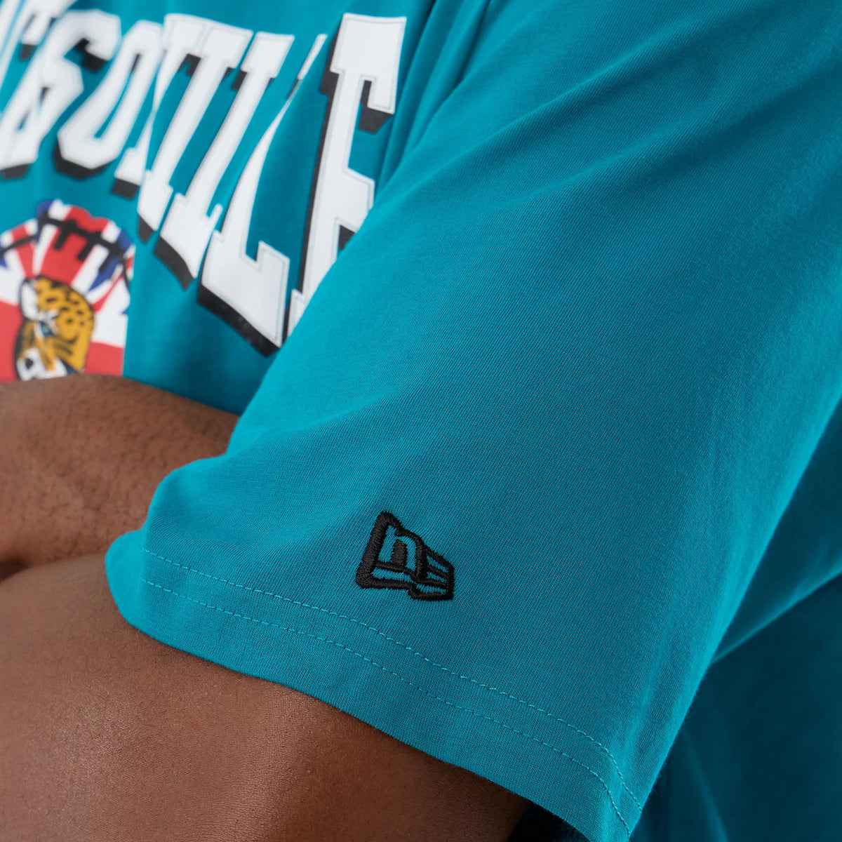 New Era Jacksonville Jaguars NFL International Series Games Turquoise Oversized T-Shirt, front three-quarter view showing Jacksonville lettering and a jaguar graphic on the chest with an embroidered New Era logo on the sleeve.