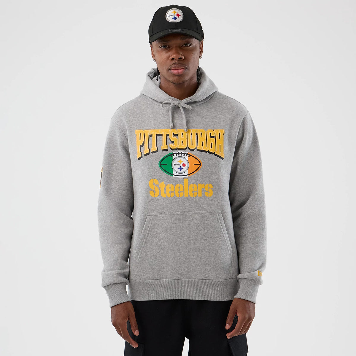 New Era Pittsburgh Steelers NFL International Series Games Grey Pullover Hoodie, front view showing Pittsburgh Steelers lettering in yellow across the chest with a football motif below, a matching embroidered logo on the left sleeve.