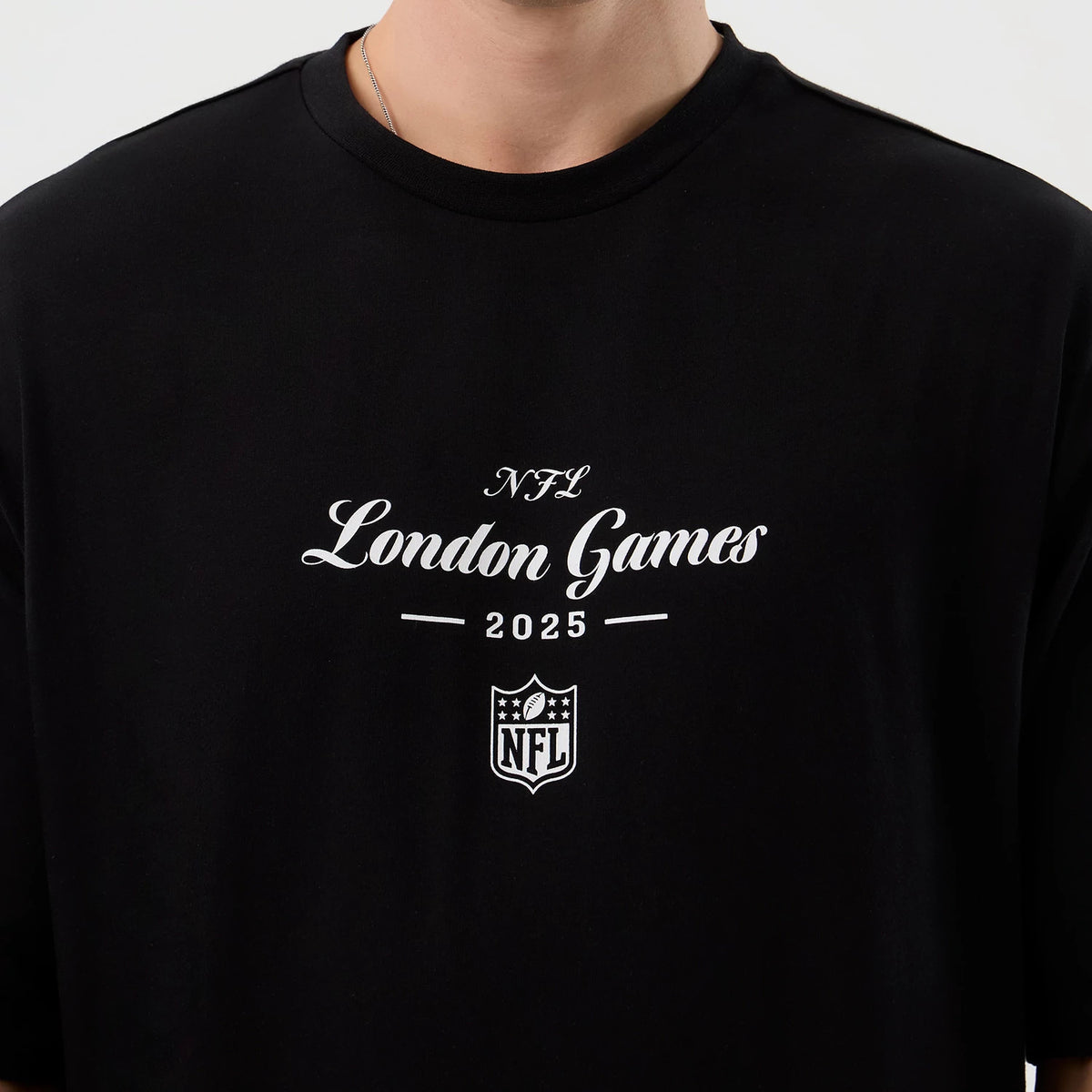 New Era London Games NFL International Series Games Black Oversized T-Shirt, front view displaying the white printed script text NFL London Games 2025 with an NFL shield logo centred just below, against a solid black background.